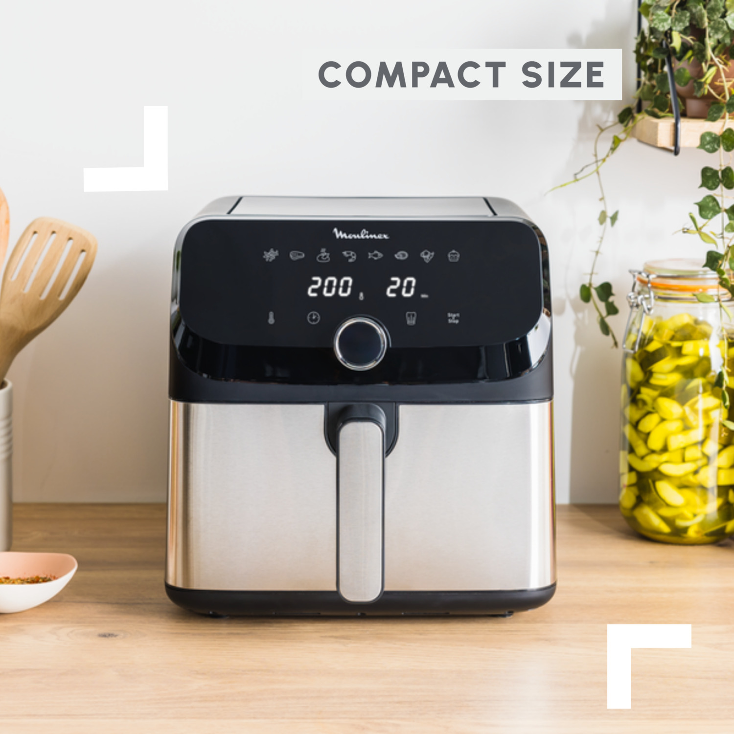 Black and silver air fryer on a wooden surface. The display shows 200 and 20.