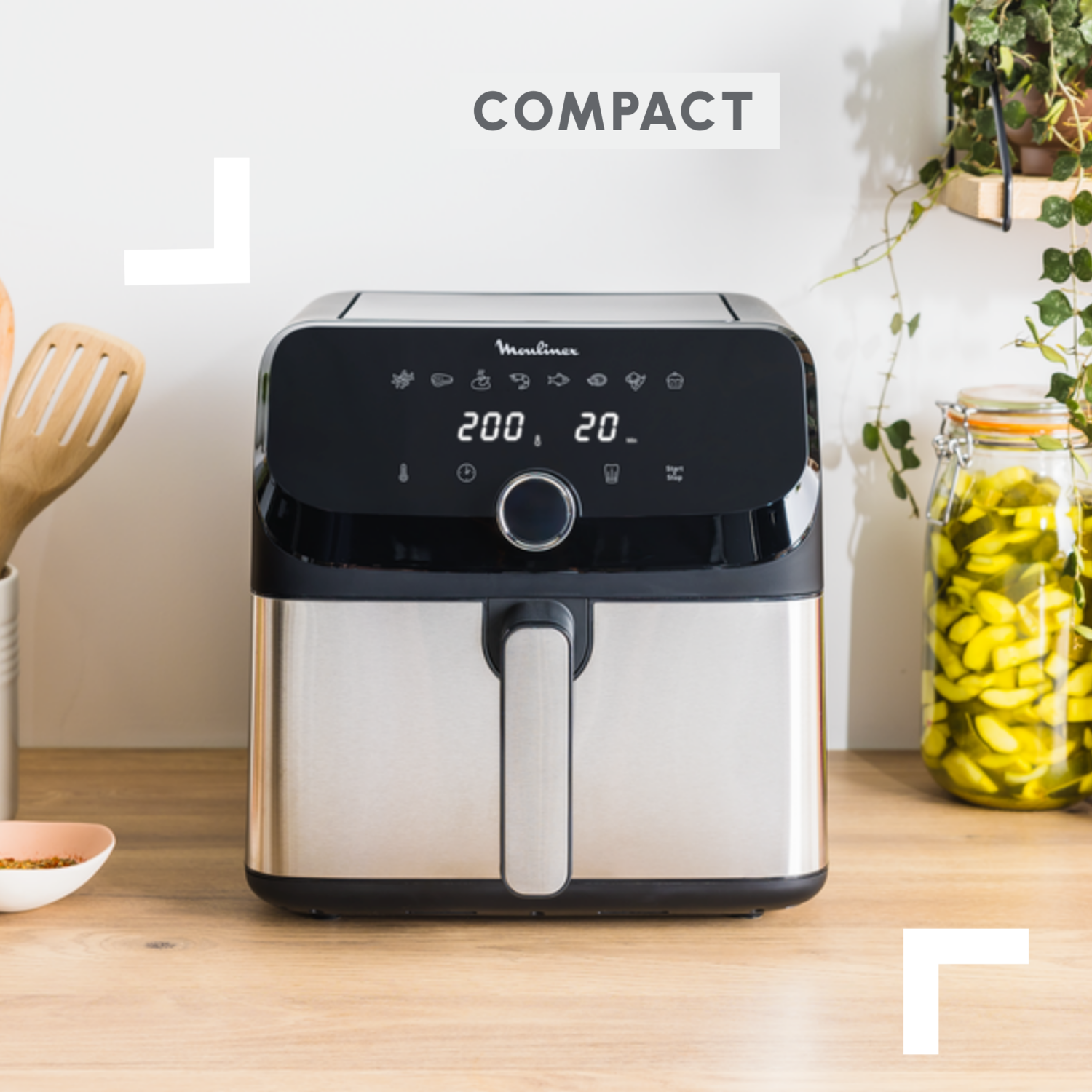 Une friteuse à air argentée et noire sur une surface en bois, avec le texte 'COMPACT'.