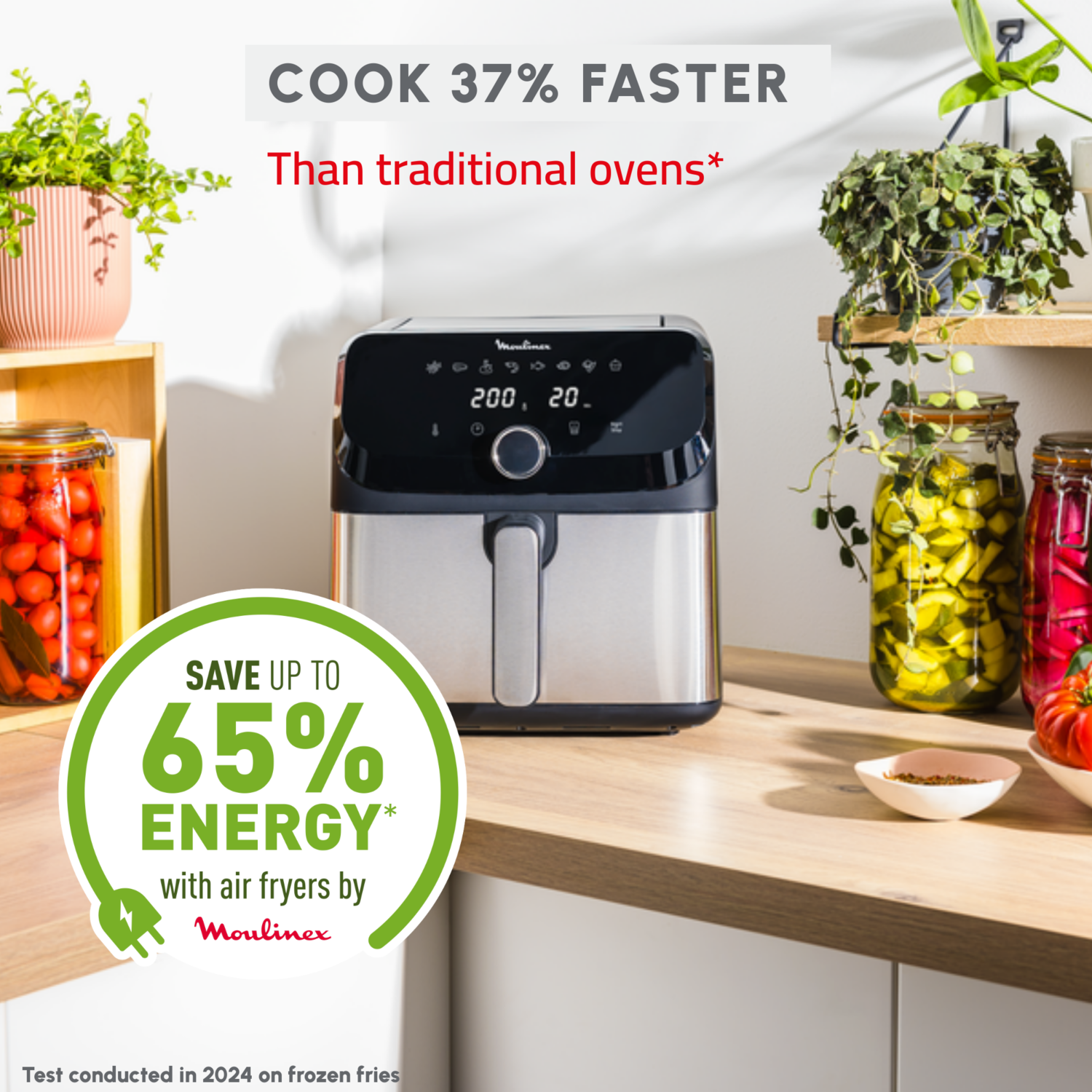 An air fryer with a digital display, on a wooden surface with plants and jars.