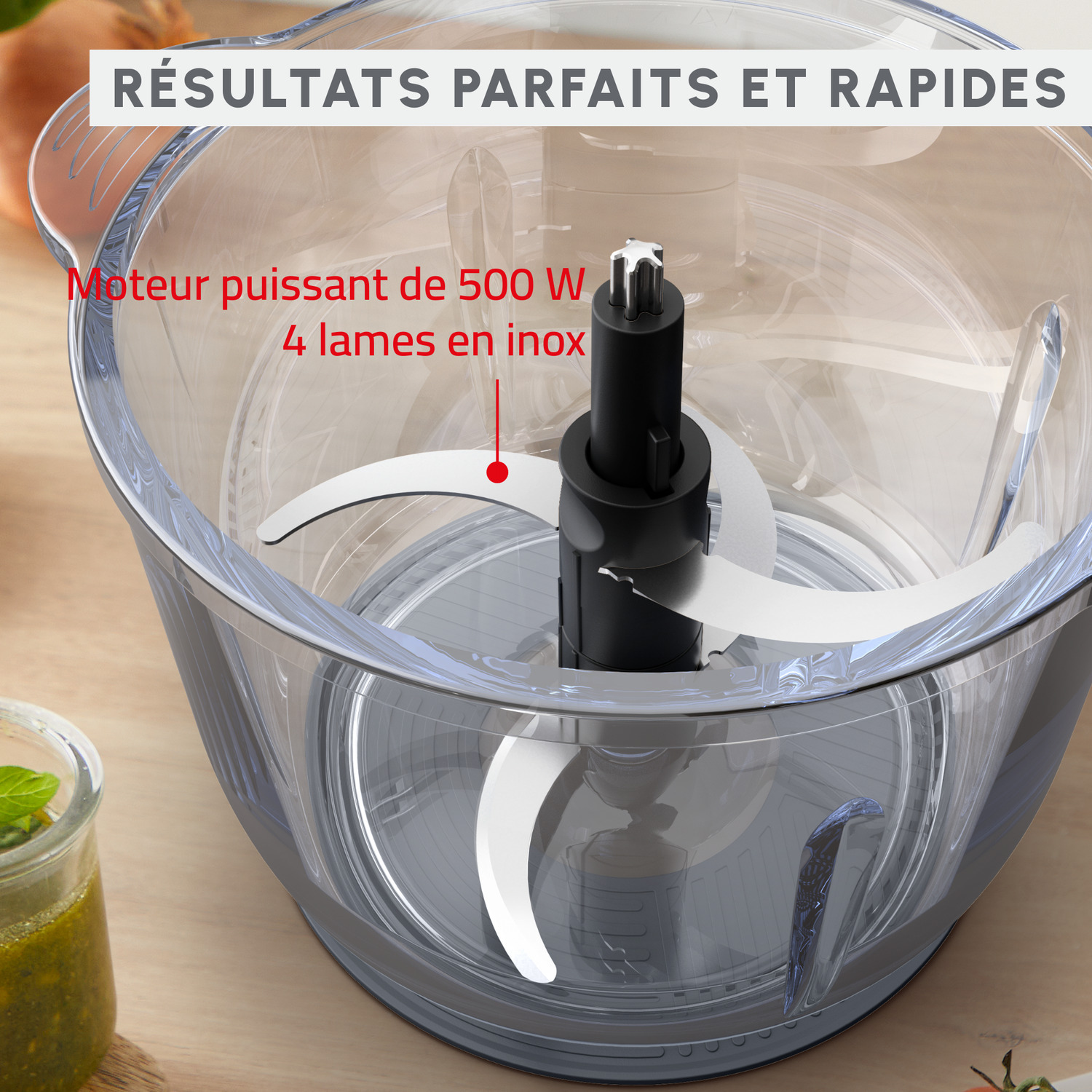 Un robot culinaire transparent avec des lames, avec texte descriptif, sur une surface en bois.
