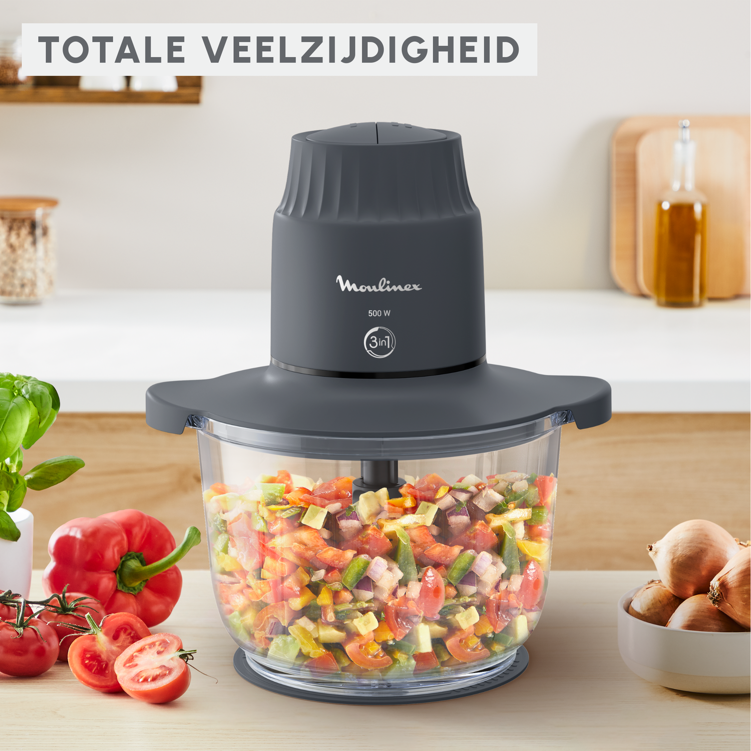 Een donkergrijze keukenmachine met een kom vol gehakte groenten.