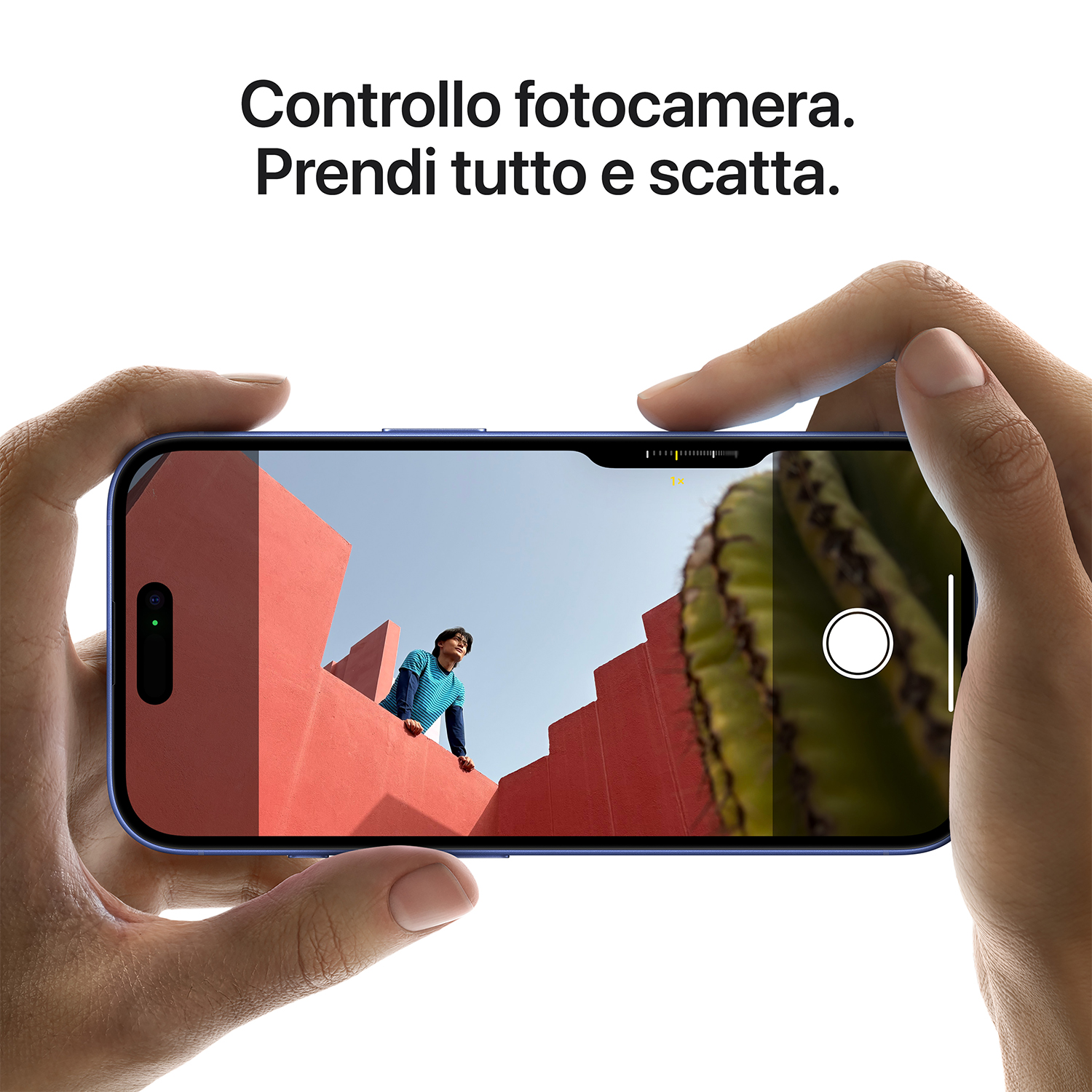 Un telefono mostra una scena con strutture rosse, un cactus e cielo blu, tenuto in mano.