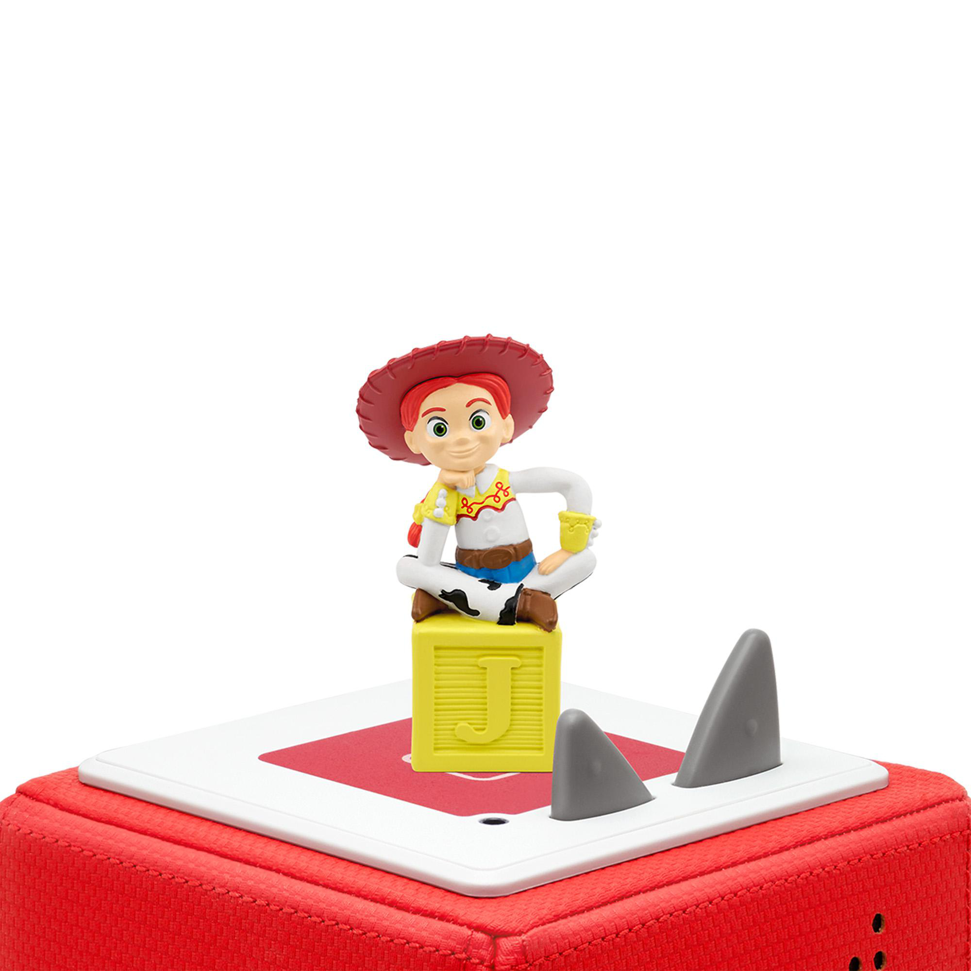 Toy Storys Jessie-Figur sitzt auf einem Spielzeugblock, mit Haifischflossen auf einer rot-weißen Oberfläche.
