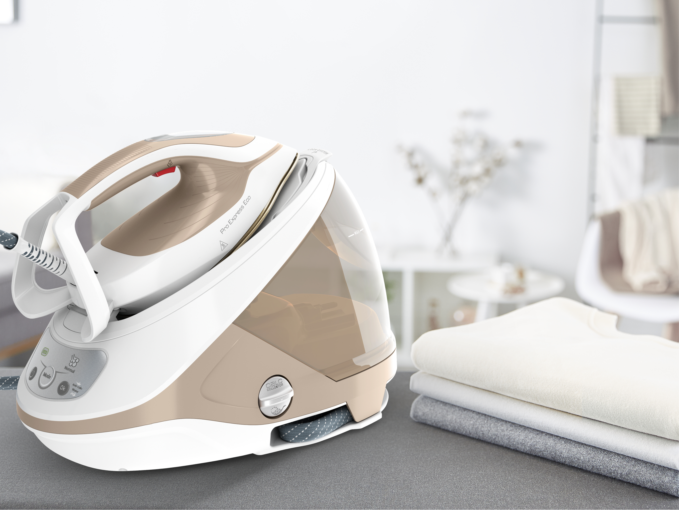 Żelazko i deska do prasowania ze stosem złożonych ubrań. Żelazko jest białe i beżowe.