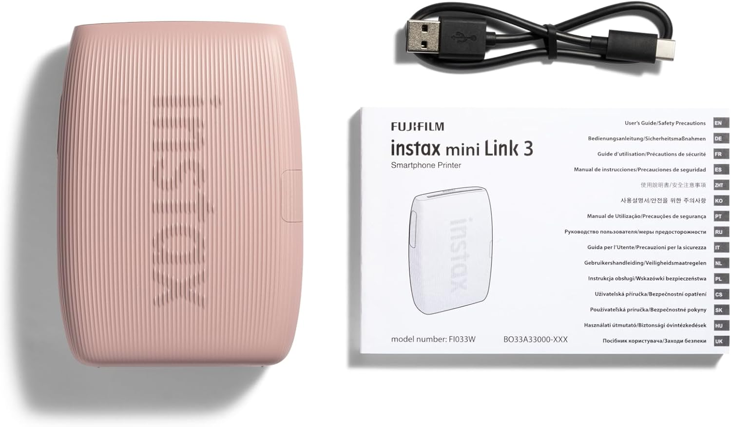 Rózsaszín Instax Mini Link 3 nyomtató, USB kábel és felhasználói útmutatók, rendezett elrendezésben.