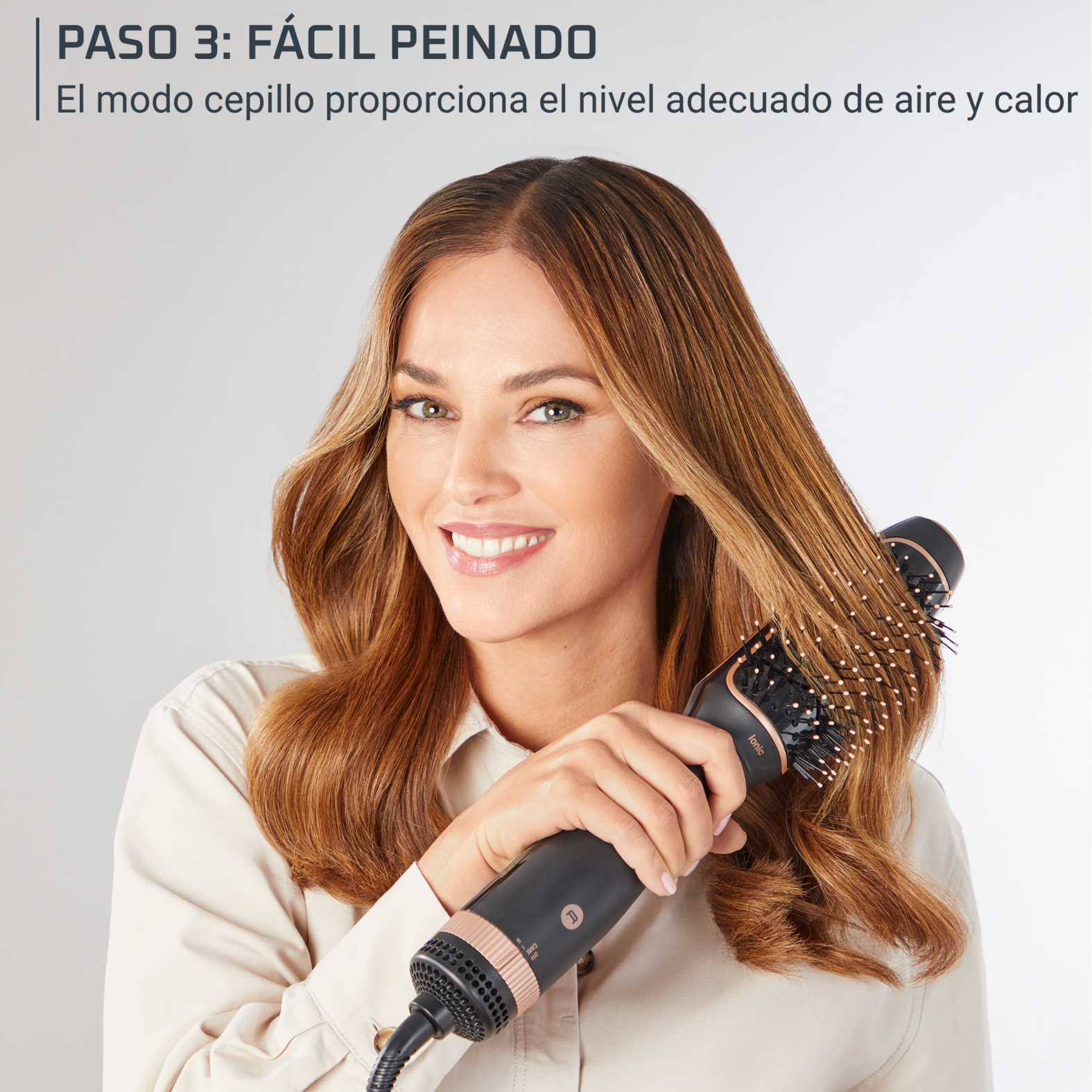 Mujer sonriendo mientras usa un secador de pelo, con cabello castaño largo, paso 3: Texto Estilizado fácil en la parte superior.