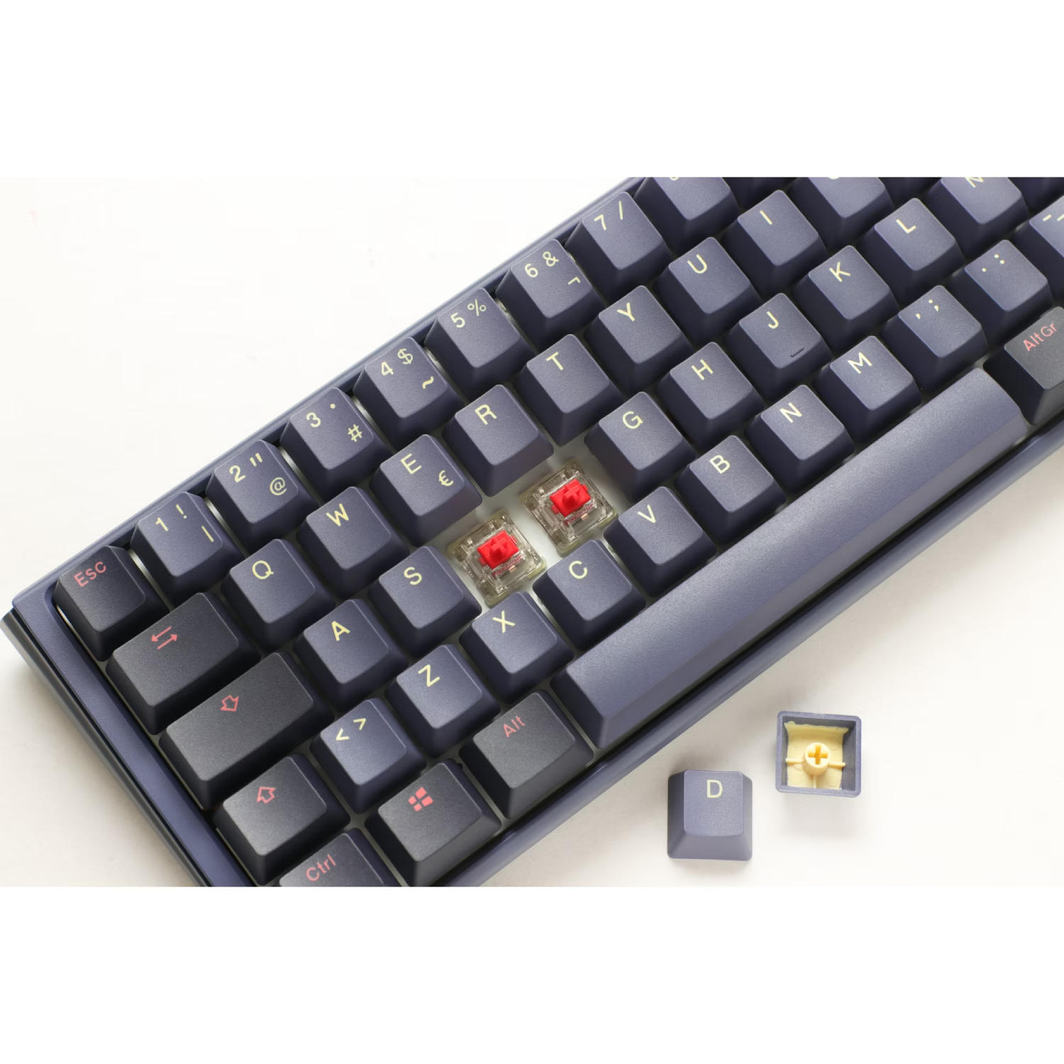 Teclado mecánico con teclas azules. Dos interruptores rojos visibles, una tecla quitada.