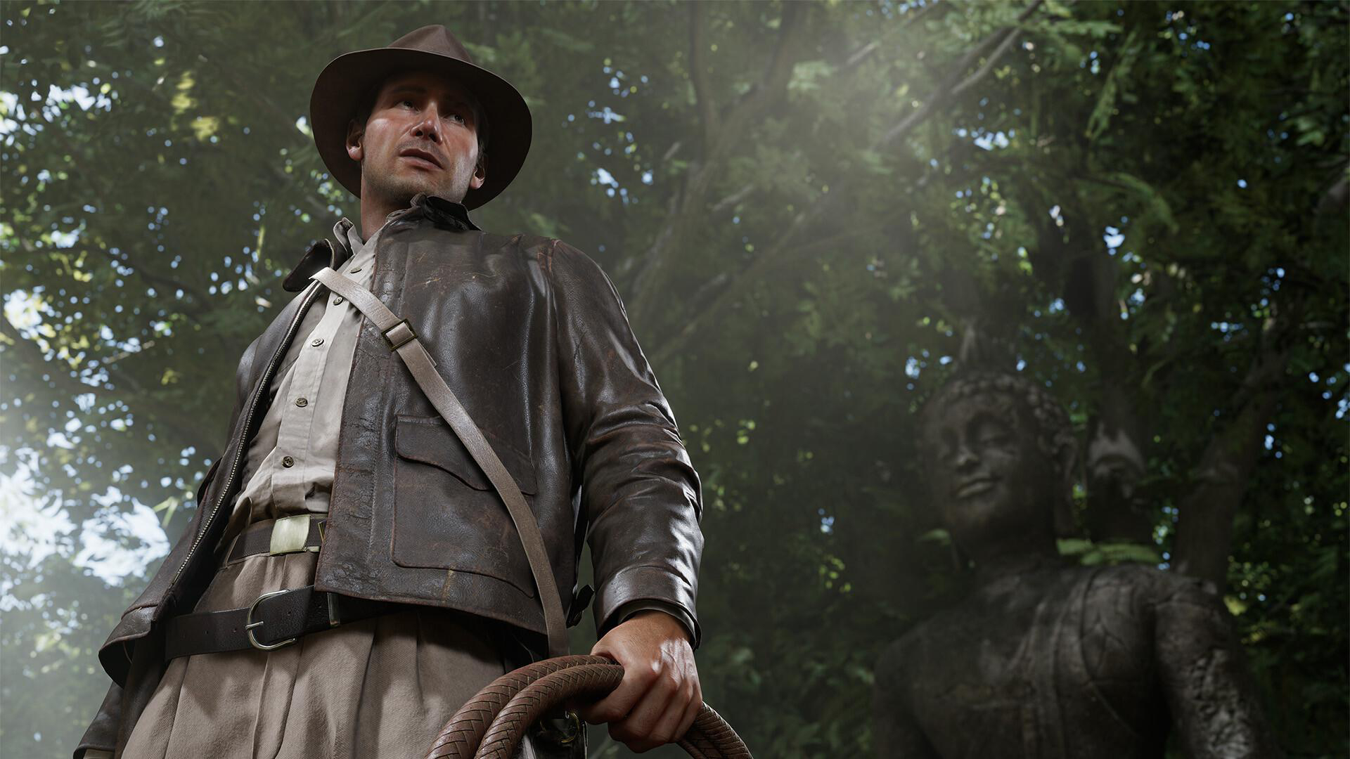 Indiana Jones mit Hut und Jacke, hält Peitsche. Statue im verschwommenen Hintergrund.