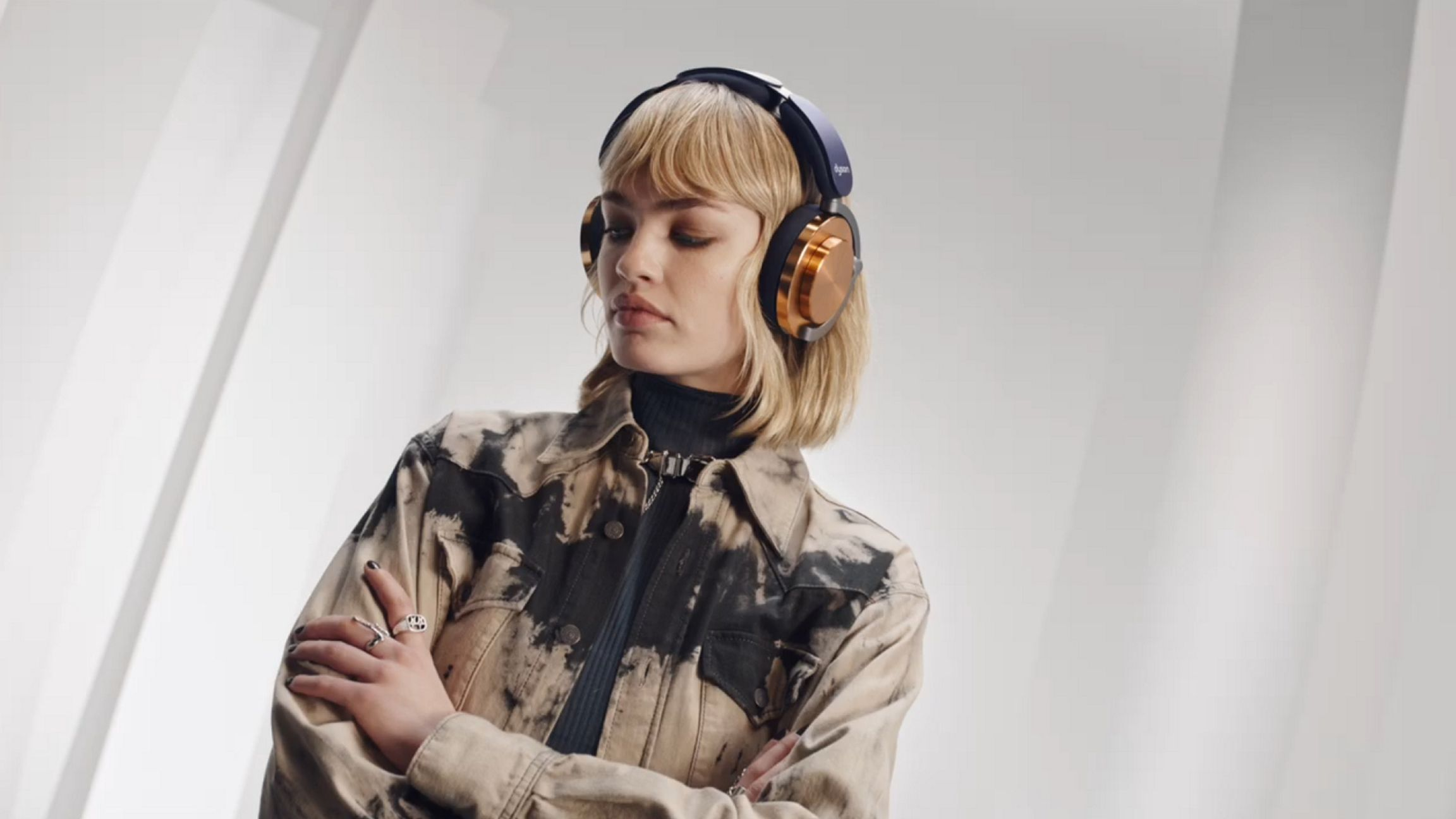 Femme portant un casque doré et bleu foncé, regardant vers le bas, avec une veste.