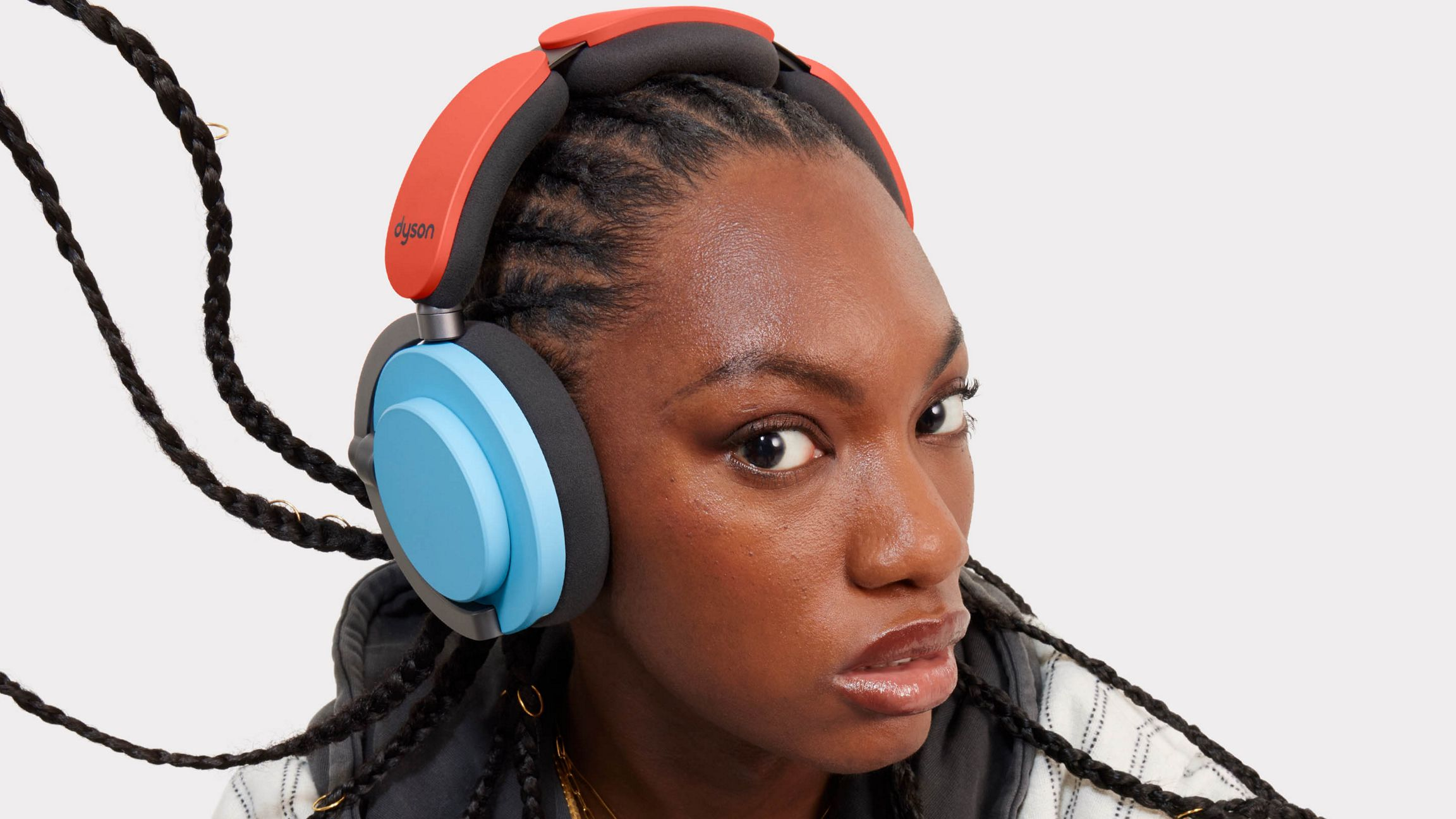 Une femme portant un casque rouge et bleu. Ses cheveux sont tressés. Elle regarde la caméra avec une expression neutre.