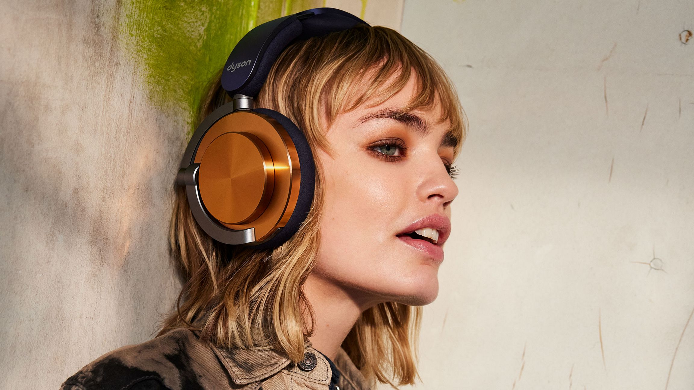 Une femme portant un casque doré et bleu marine regardant vers la droite avec des cheveux blonds courts.