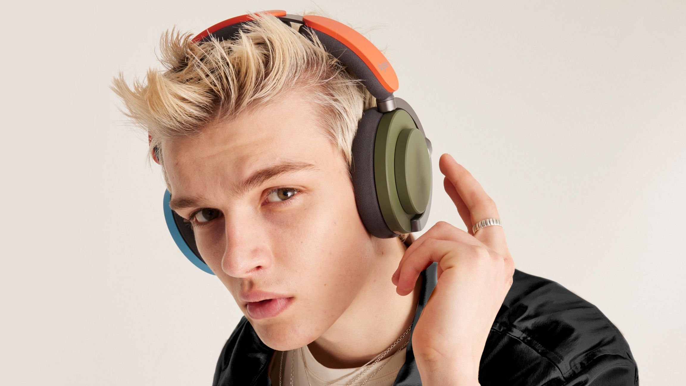 Jeune homme aux cheveux blonds portant un casque, accents orange et bleu, regardant la caméra.
