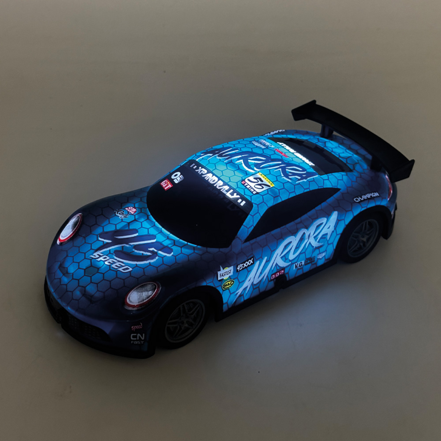 Een blauwe speelgoed raceauto met een zwarte spoiler, op een oppervlak met wit licht.