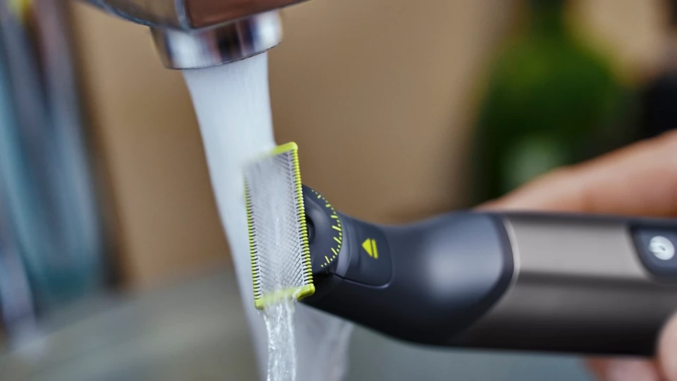 Zbliżenie czarno-żółtej golarki elektrycznej, która jest płukana wodą.