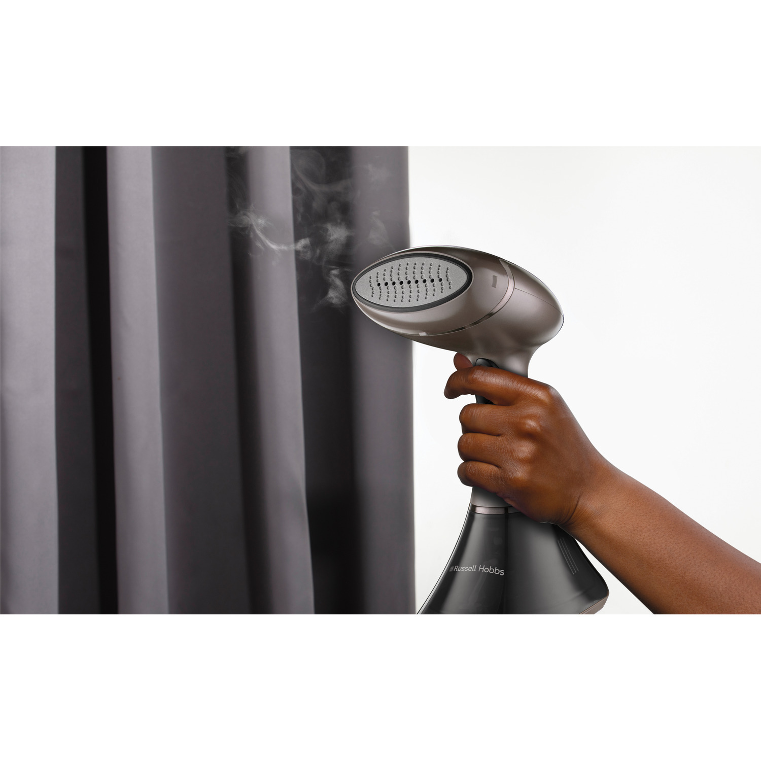 Hand holding a steamer. Steam coming out, ironing a curtain.