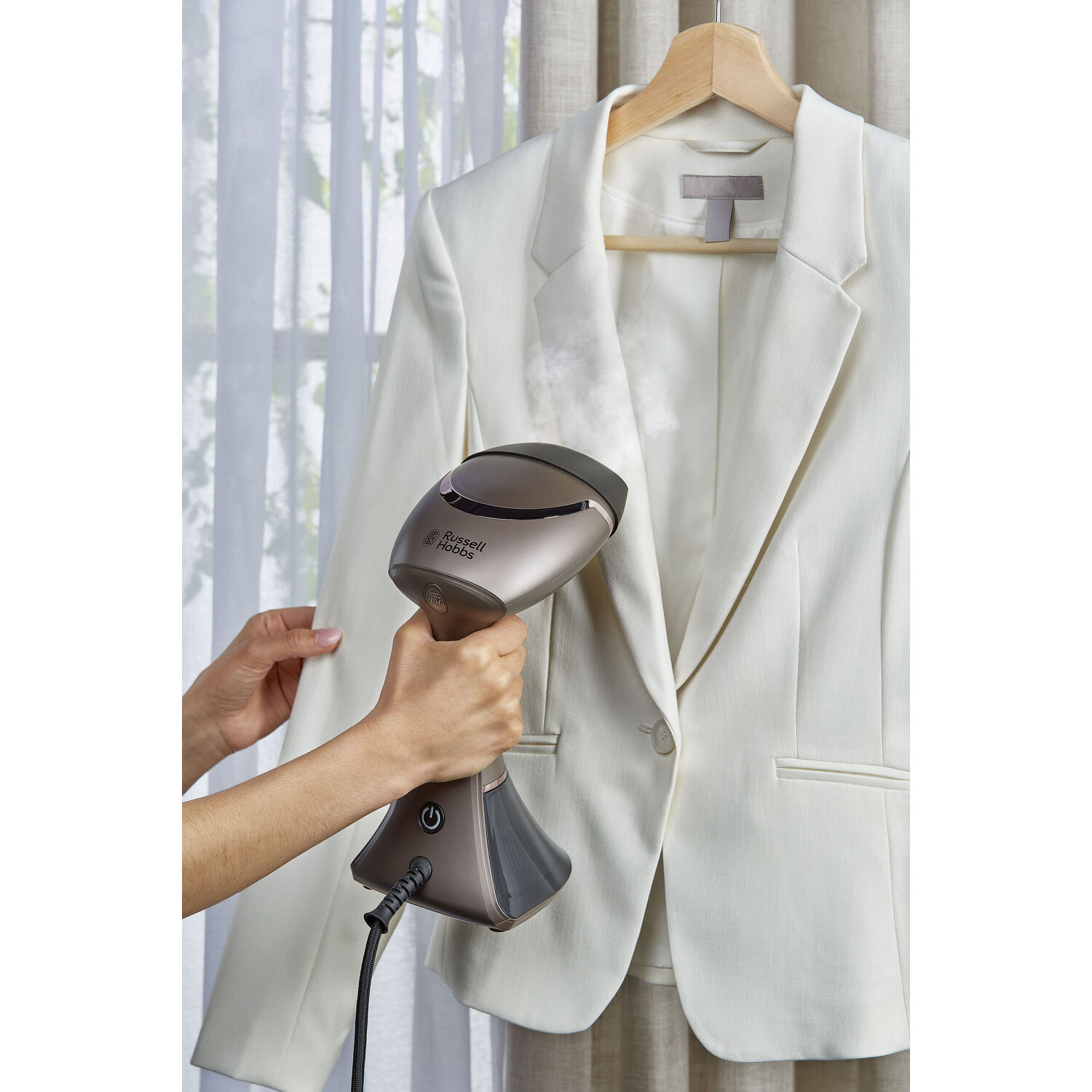 A white jacket is being steamed with a hand-held steamer.