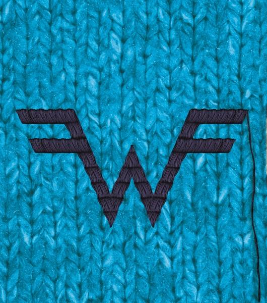 Textil mit blauem Strickmuster und einem lila gestickten 'W'-Logo.