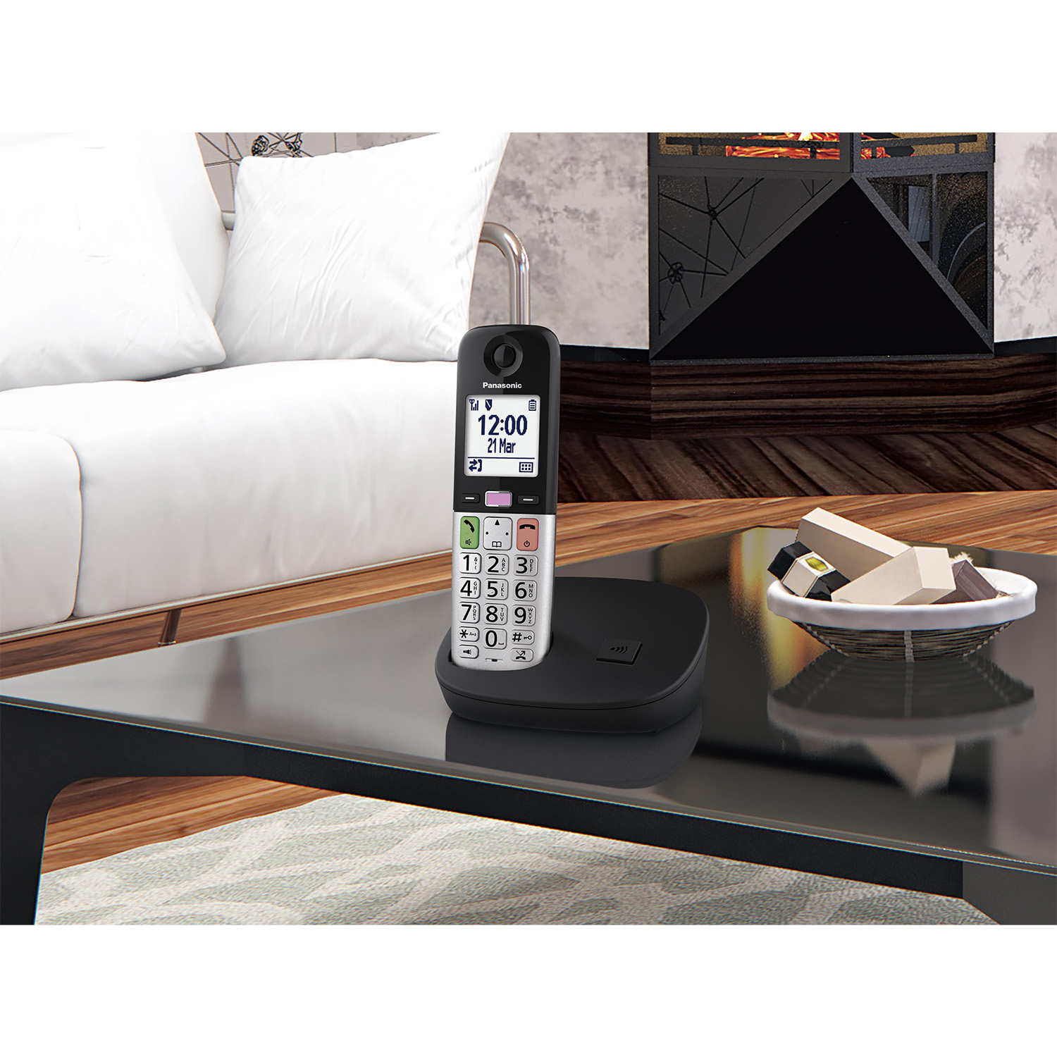Telefono cordless nero sulla sua base, su un tavolo con altri oggetti.