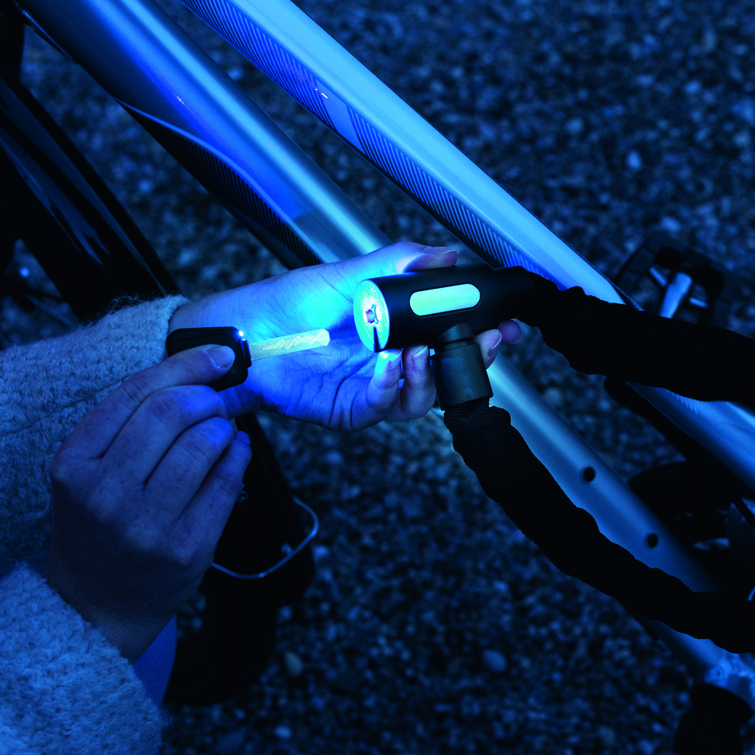 Persoon ontgrendelt 's nachts een fietsslot met een sleutel. Slot en sleutel worden verlicht.