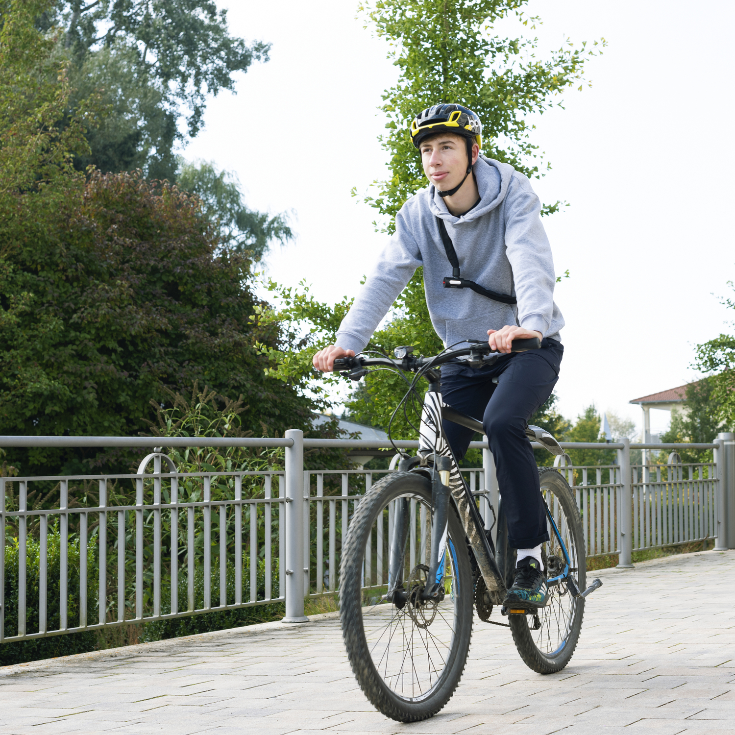 Een persoon die op een verhard pad fietst, met een helm en een grijze hoodie.