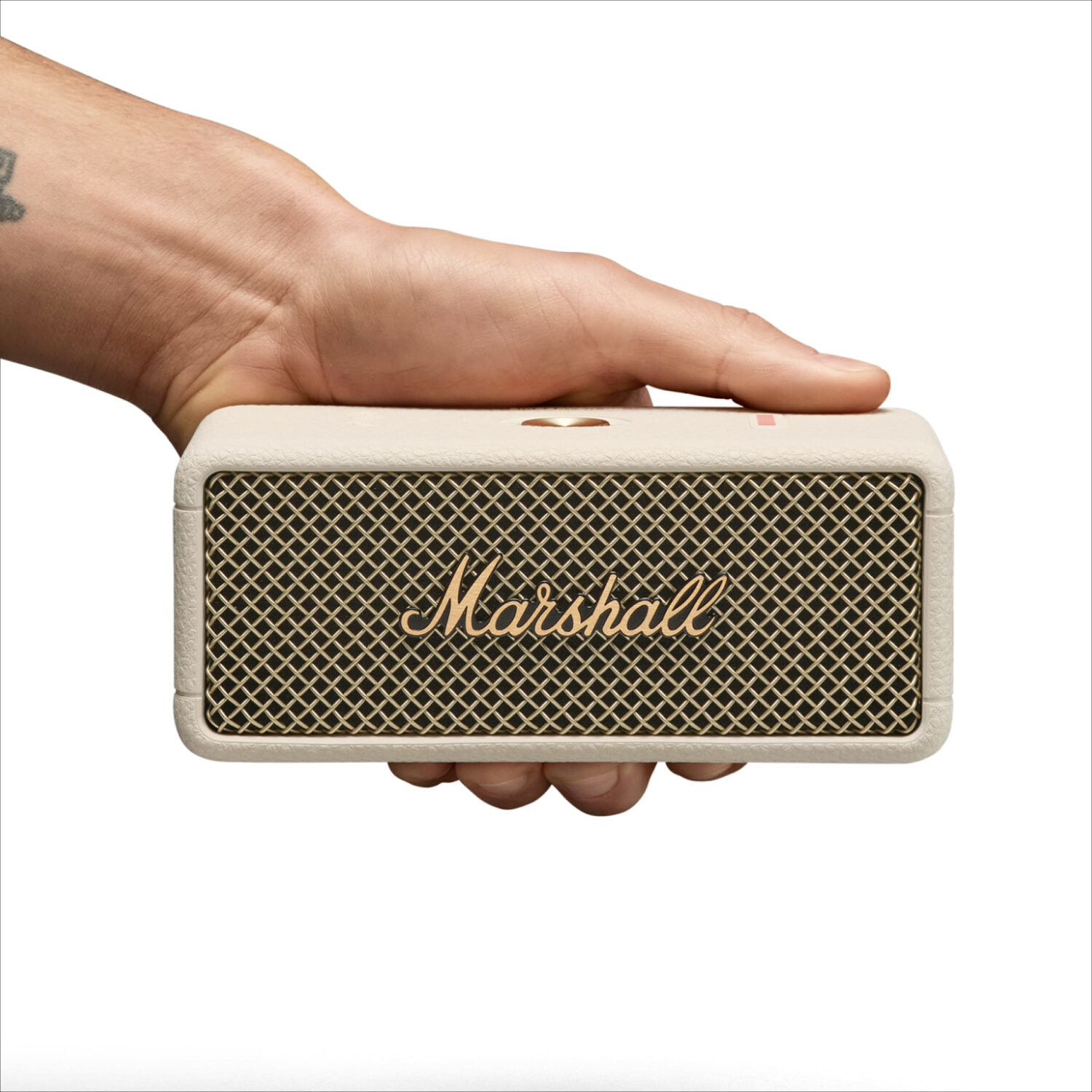 A person holding a Marshall speaker. Speaker is cream-colored with a mesh grill.