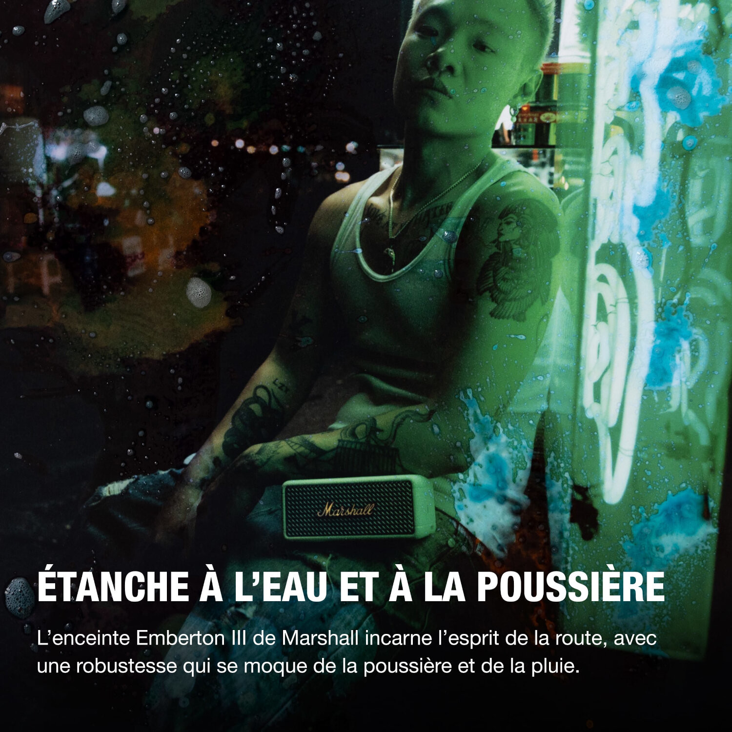 Homme tatoué tenant un haut-parleur portable. Lumières néon créent un fond futuriste.