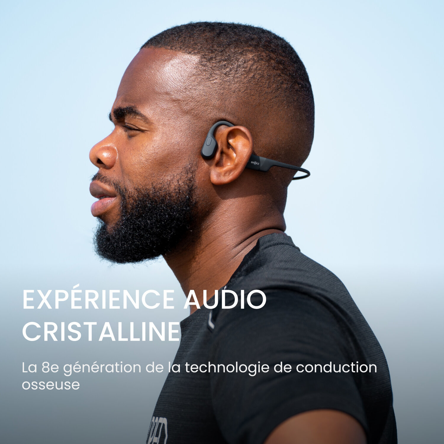 Homme avec casque à conduction osseuse noir, ciel bleu en arrière-plan. Texte : expérience audio cristalline.