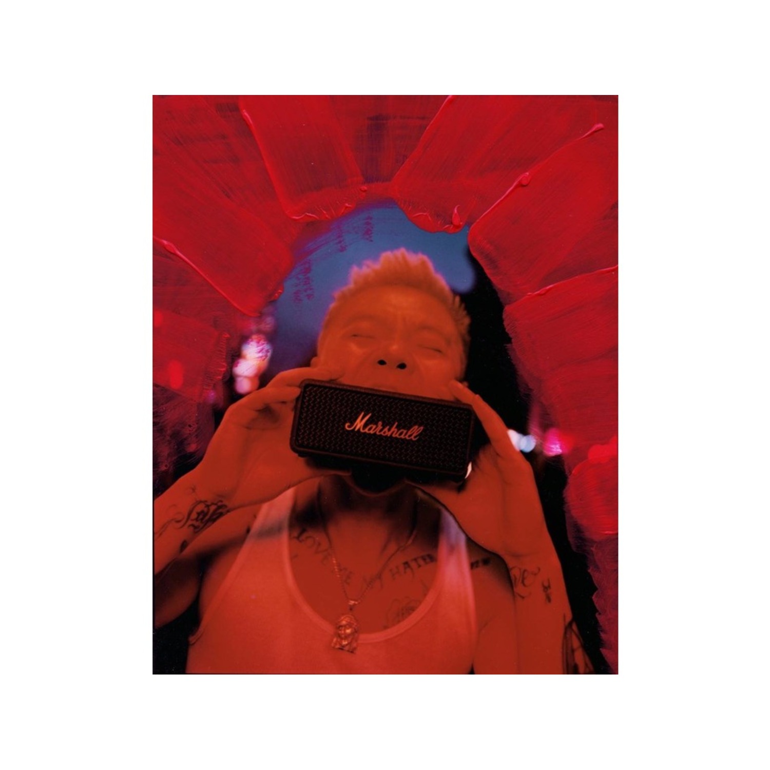 A person holding a black Marshall speaker to their mouth, with a red abstract background.