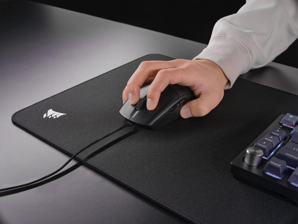 Die Hand einer Person, die eine Computermaus auf einem schwarzen Mauspads benutzt.