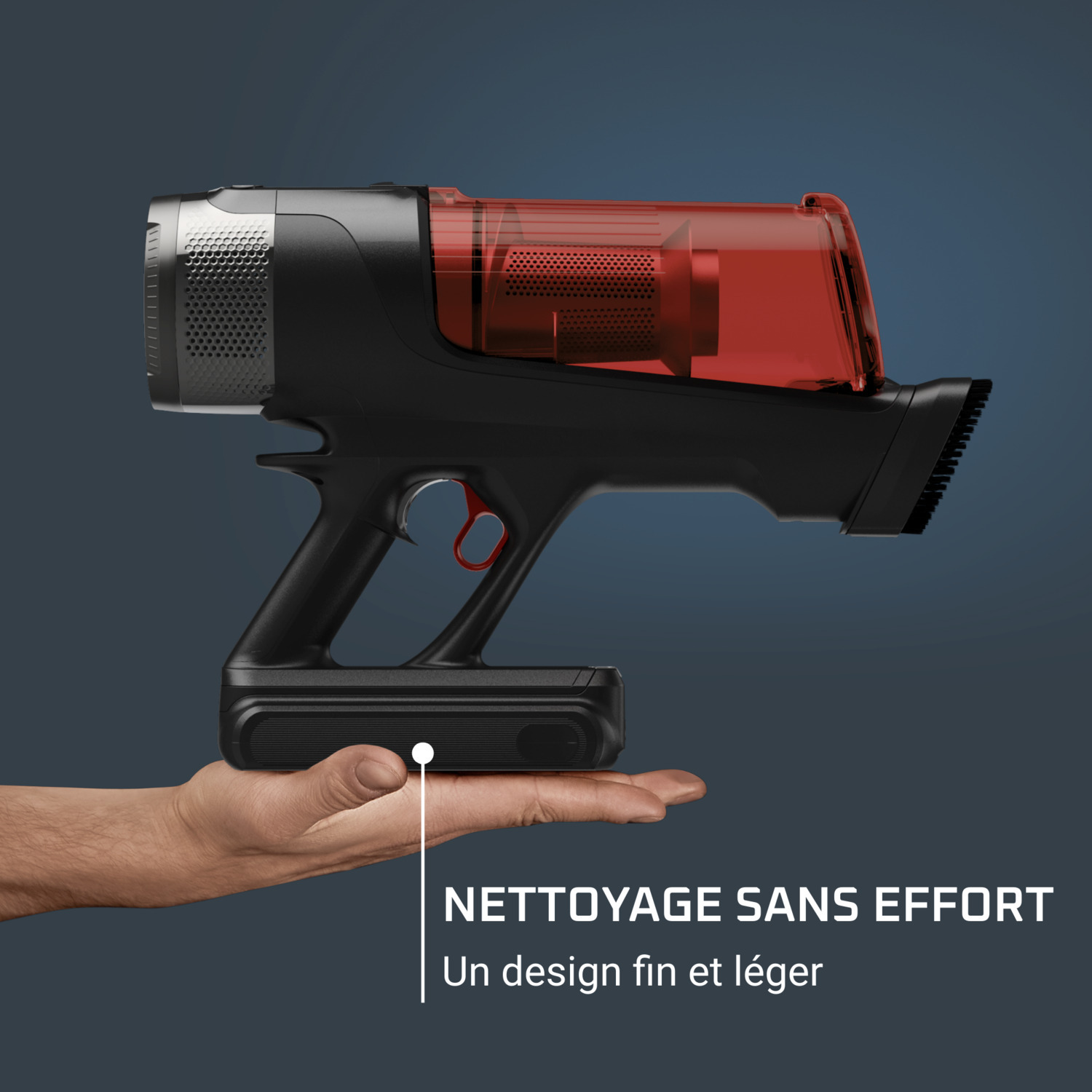 Main tenant un aspirateur noir et rouge. L'aspirateur a un conteneur à poussière rouge transparent.