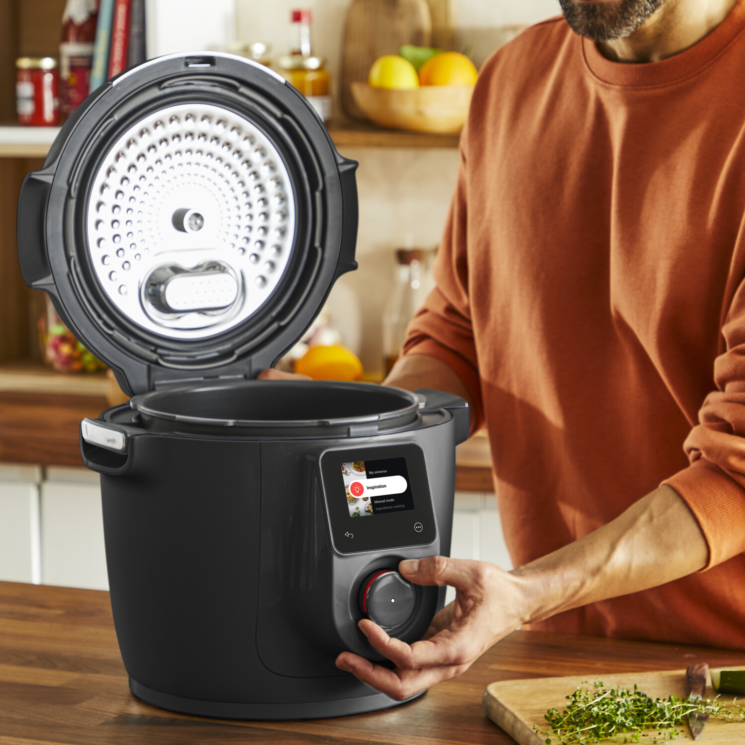 Homme utilisant une cuisinière intelligente noire avec couvercle ouvert sur un comptoir en bois.