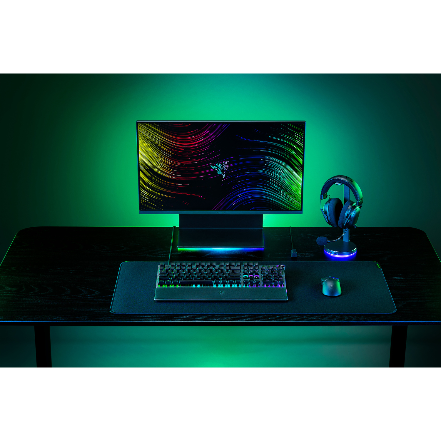 Een bureau-opstelling met een monitor, toetsenbord, muis en koptelefoon. Groene en blauwe verlichting wordt gebruikt.