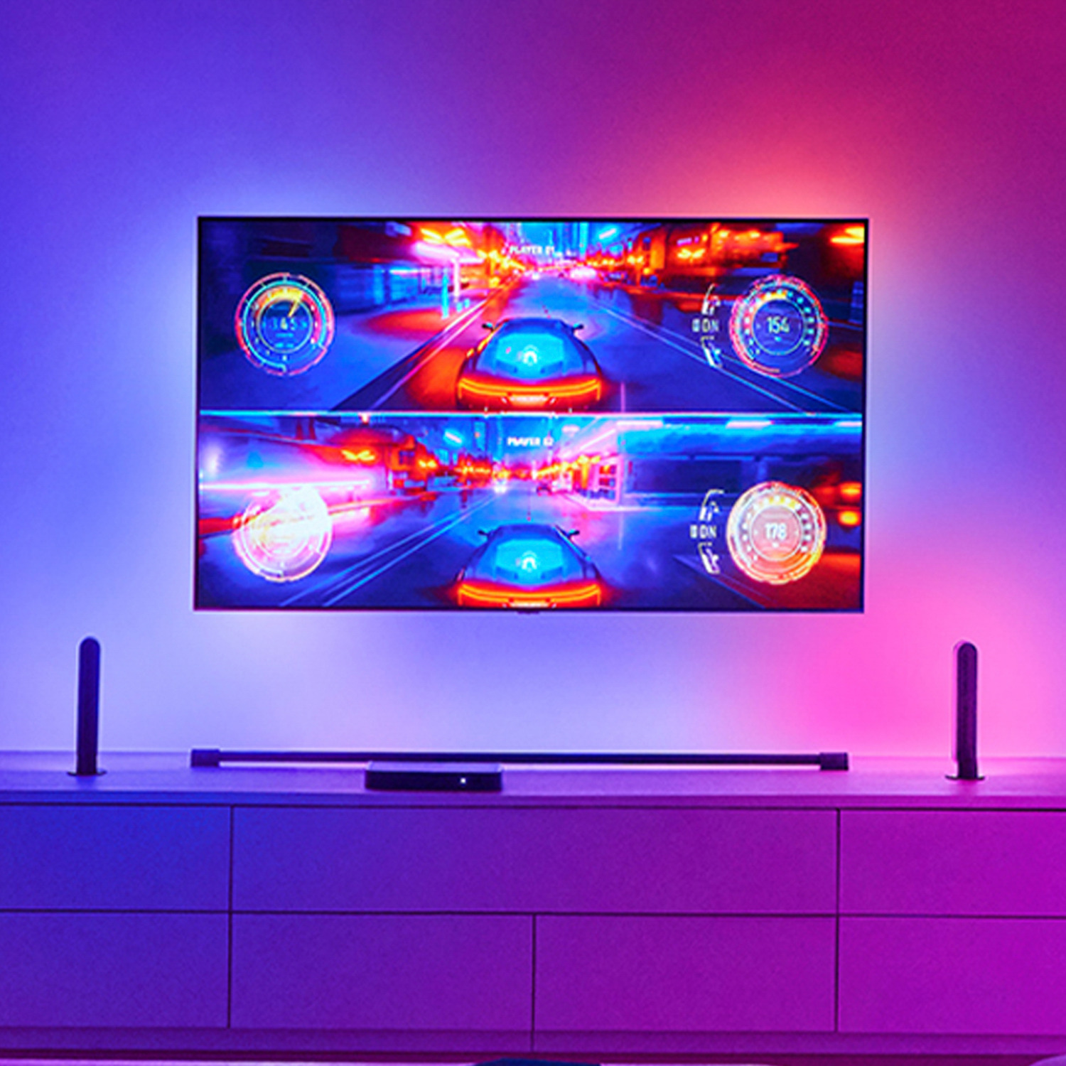 Une TV affiche un jeu de course. La lumière ambiante crée une lueur violette et rouge.