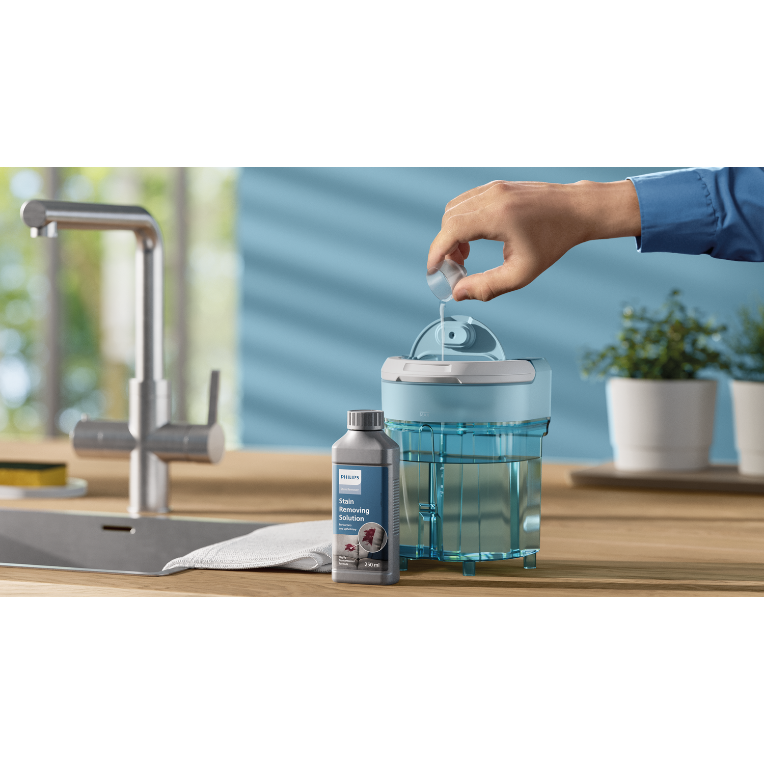 A person pouring liquid into a blue and white appliance on a wooden countertop, with a bottle.