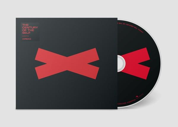 CD borító fekete háttérrel és egy piros X alakzattal. A CD mellette van.