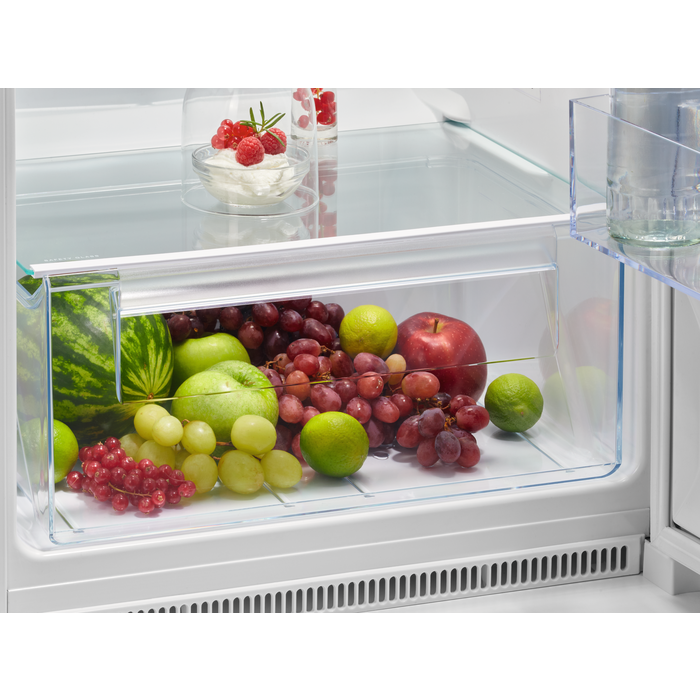 Cajón de nevera lleno de frutas: manzanas verdes, uvas y más.
