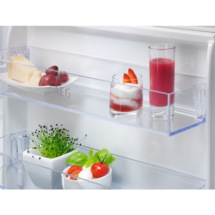 Primer plano del interior de una nevera con estantes que contienen alimentos como queso, uvas y zumo.