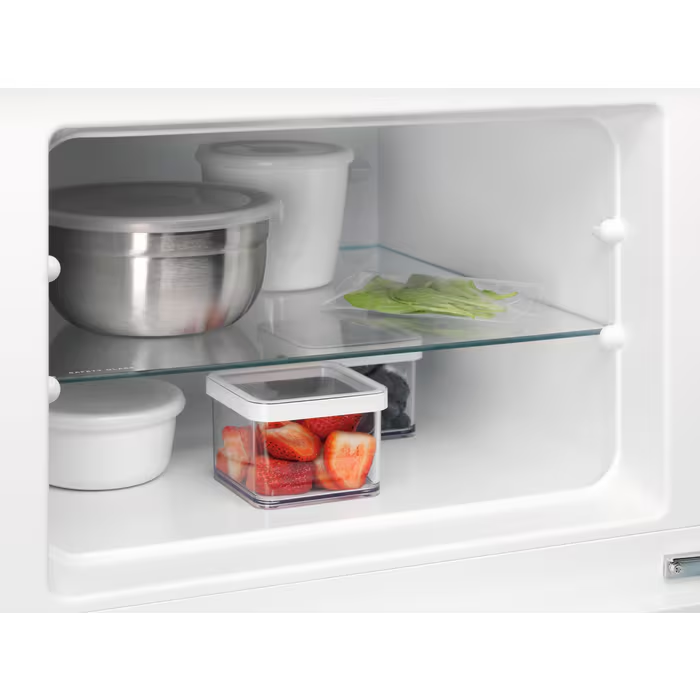 Dentro de un refrigerador con estantes que contienen recipientes de comida, incluyendo fresas.