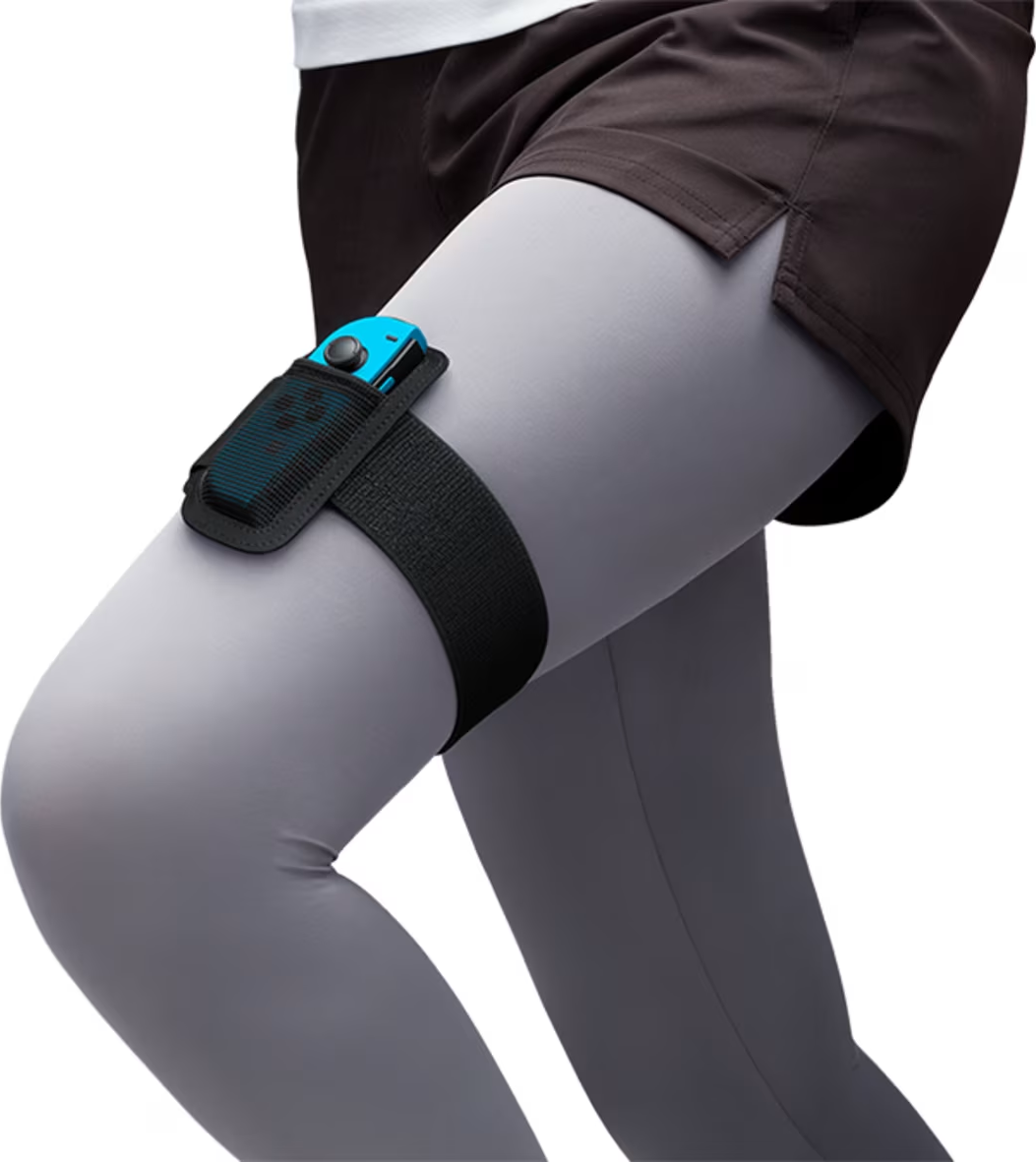 Eine Person trägt einen schwarzen Riemen mit einem Controller am Oberschenkel, graue Leggings.