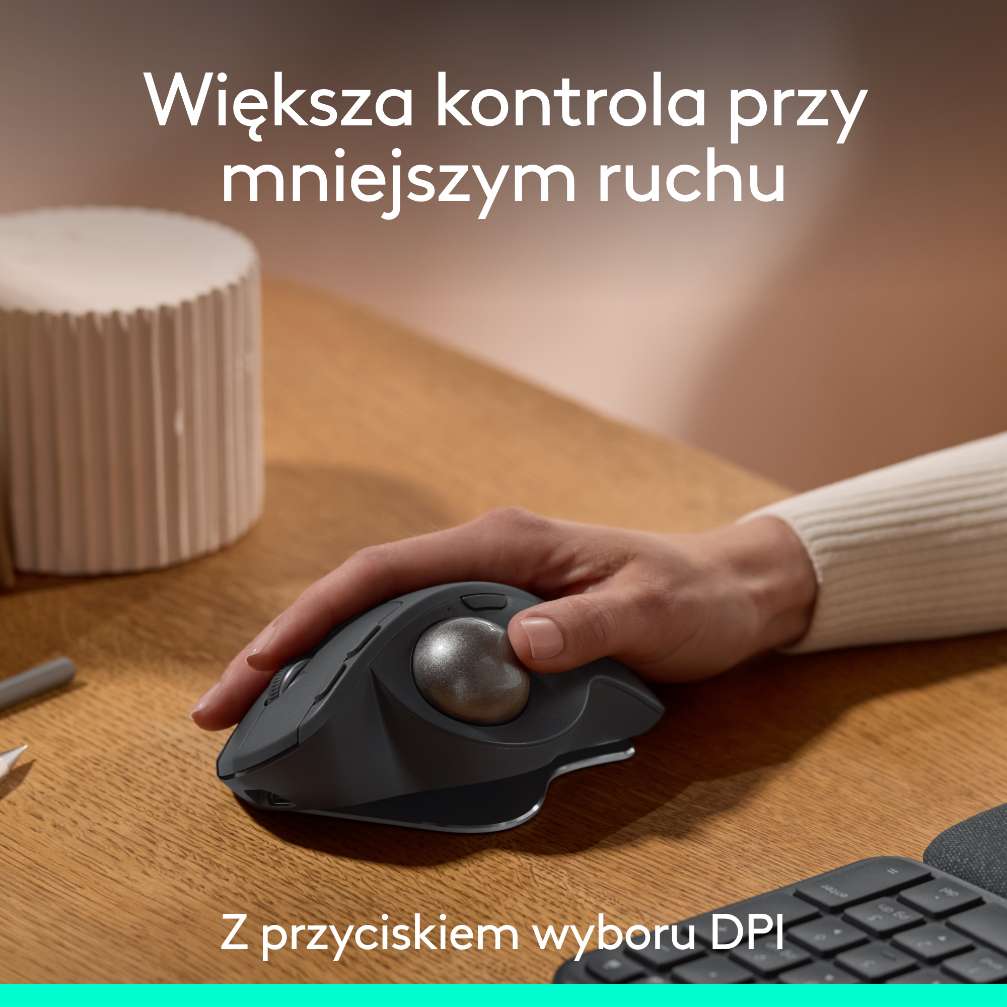 Dłonie używają ciemnoszarej myszy trackball na biurku.