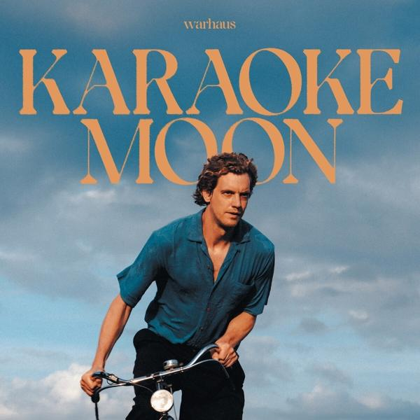 Albumcover: Mann auf Fahrrad, Titel 'Karaoke Moon' und blauer Himmel im Hintergrund.
