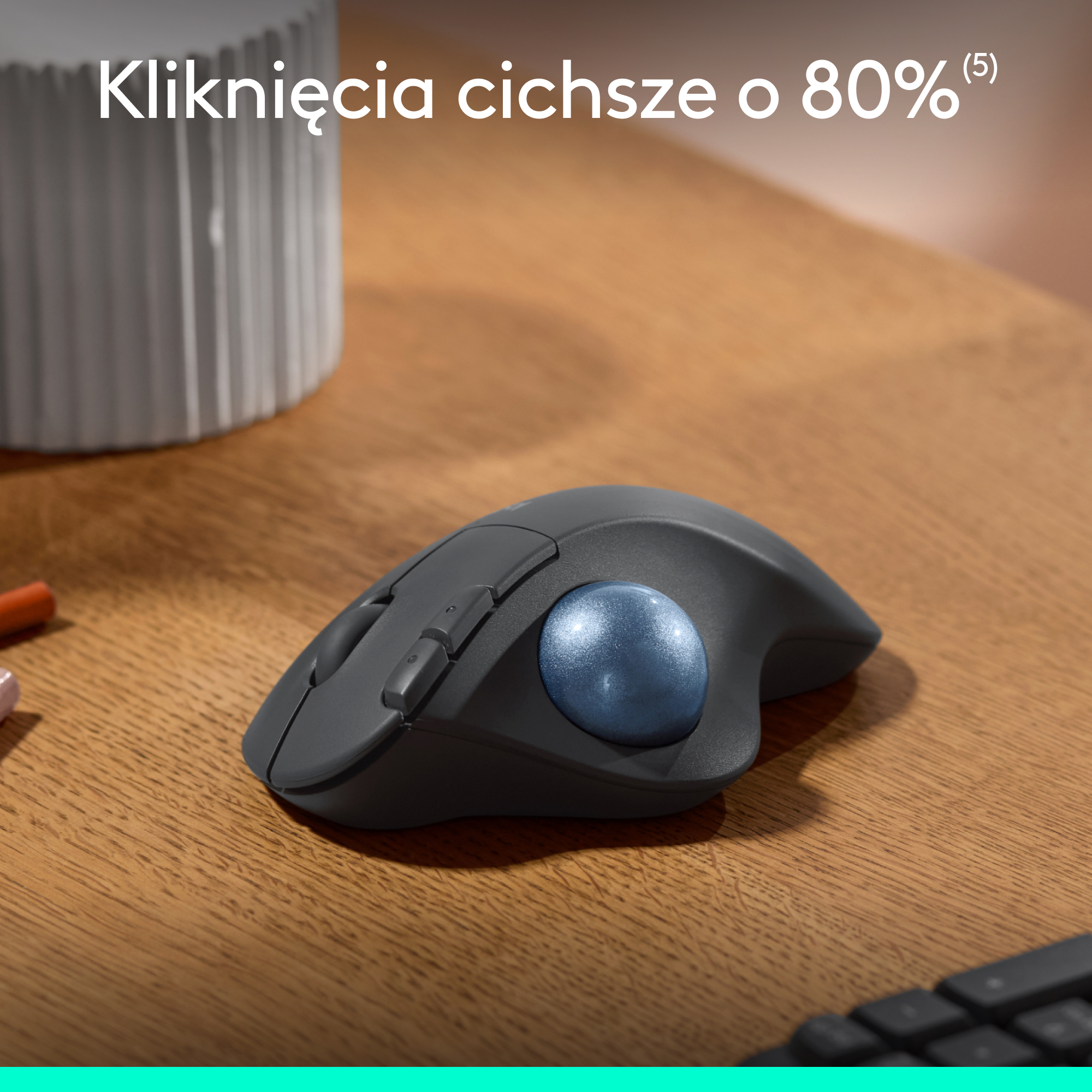 Ciemnoszara mysz trackball z niebieską kulką. Na drewnianym stole. Tekst: Kliknięcia cichsze o 80%.