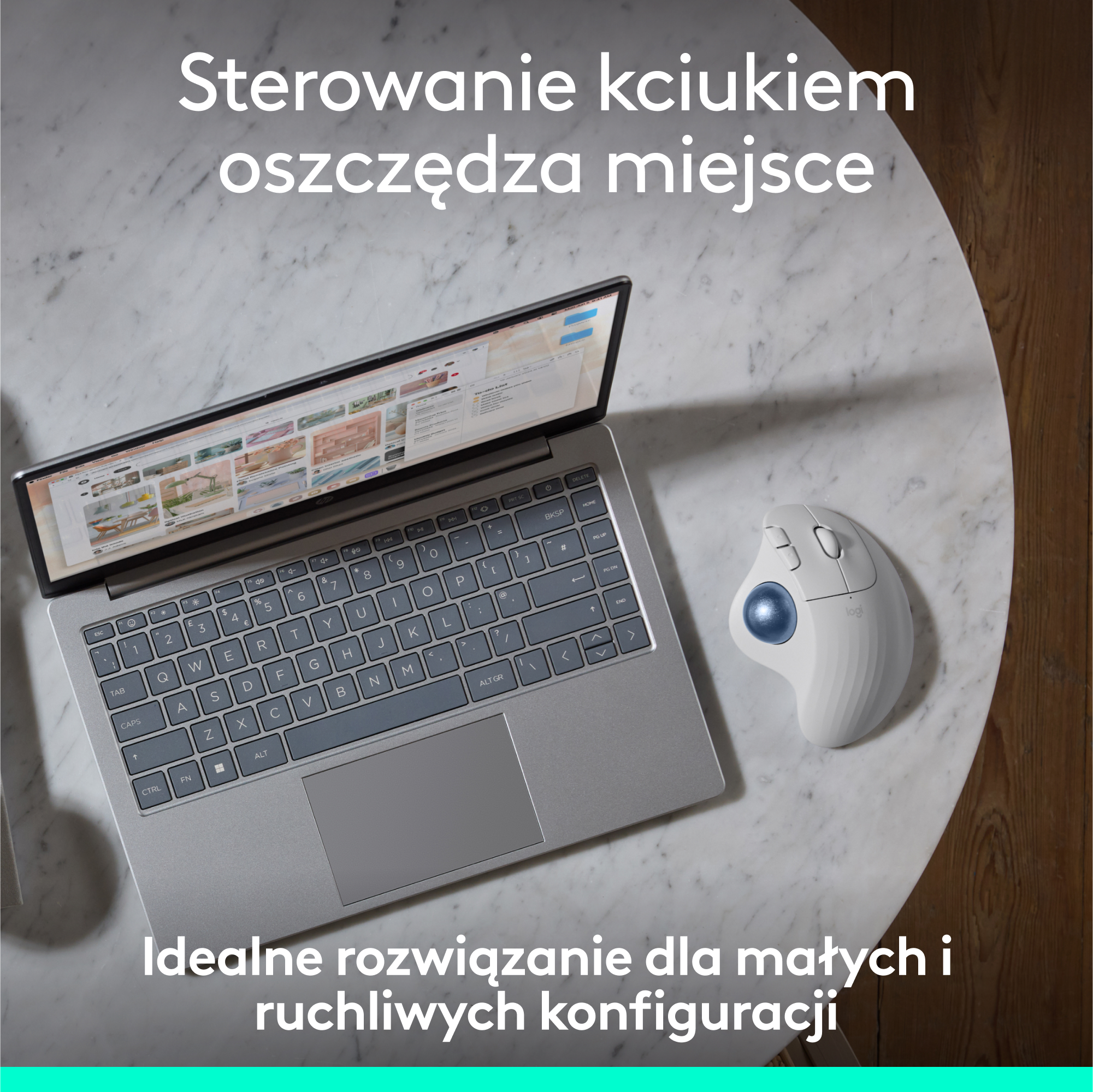 Laptop i mysz trackball na białym stole. Tekst jest po polsku.