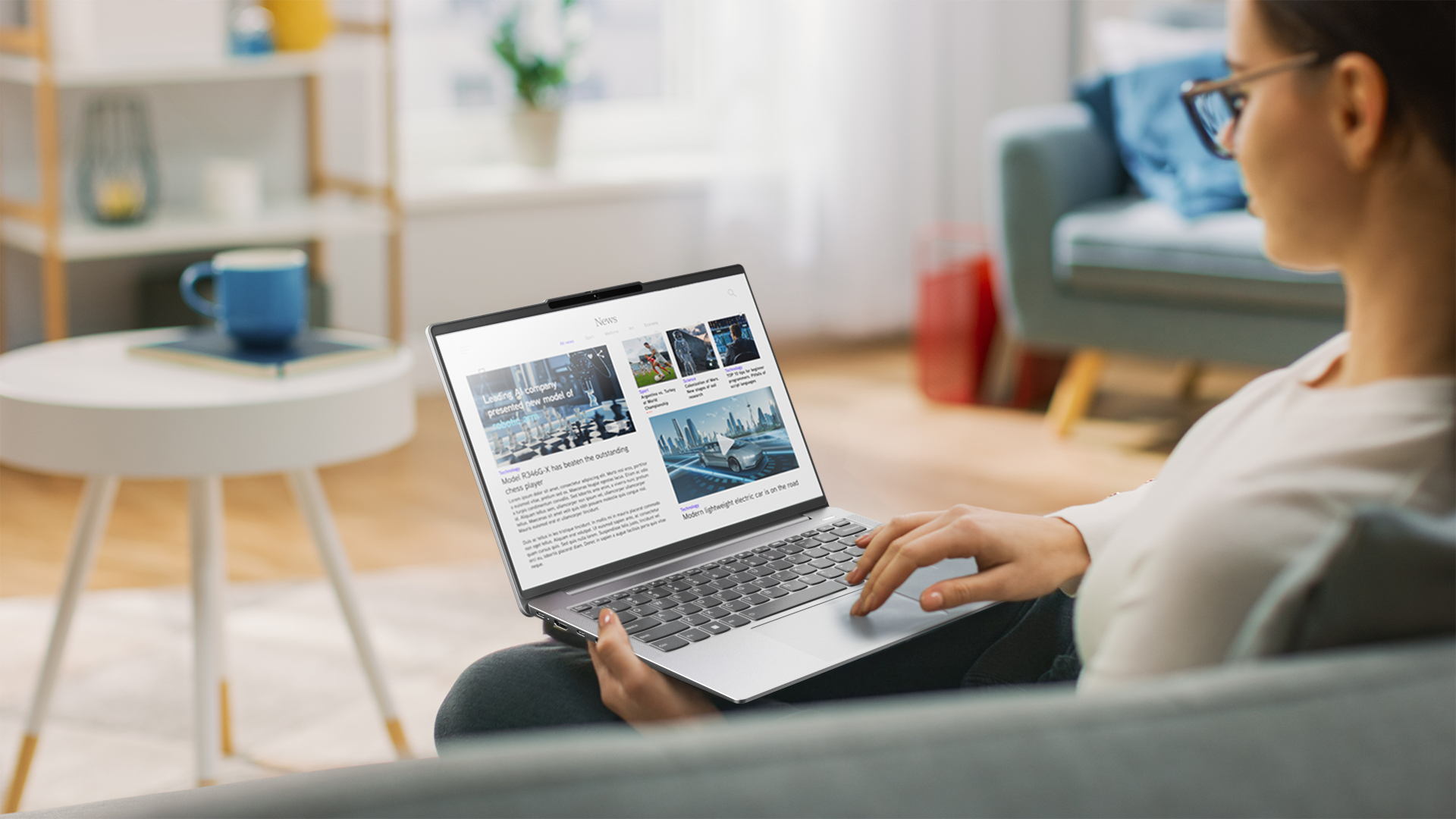 Eine Person, die ein Laptop auf einem Sofa benutzt und Nachrichtenartikel auf dem Bildschirm liest.