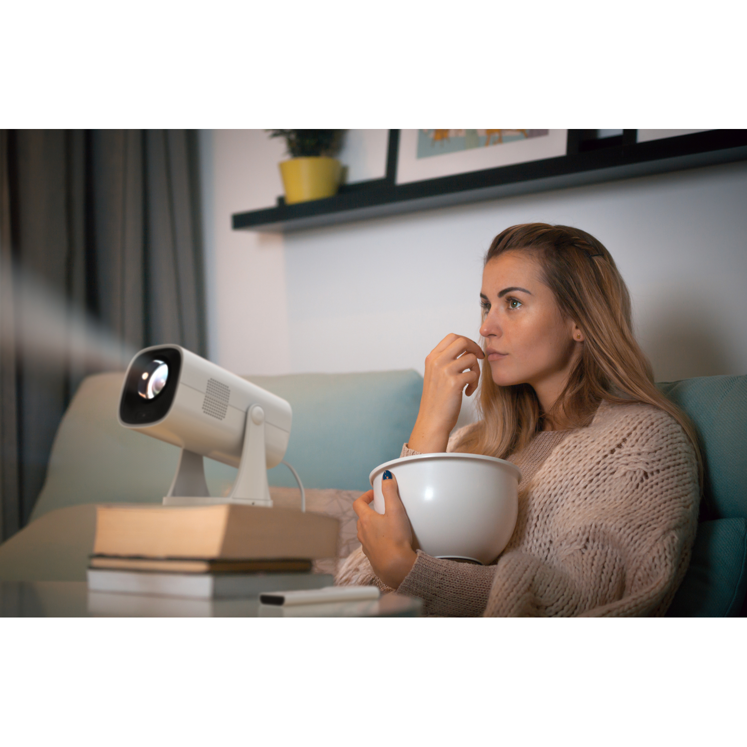 Woman watches a movie on a projector while eating popcorn, in a living room scene.