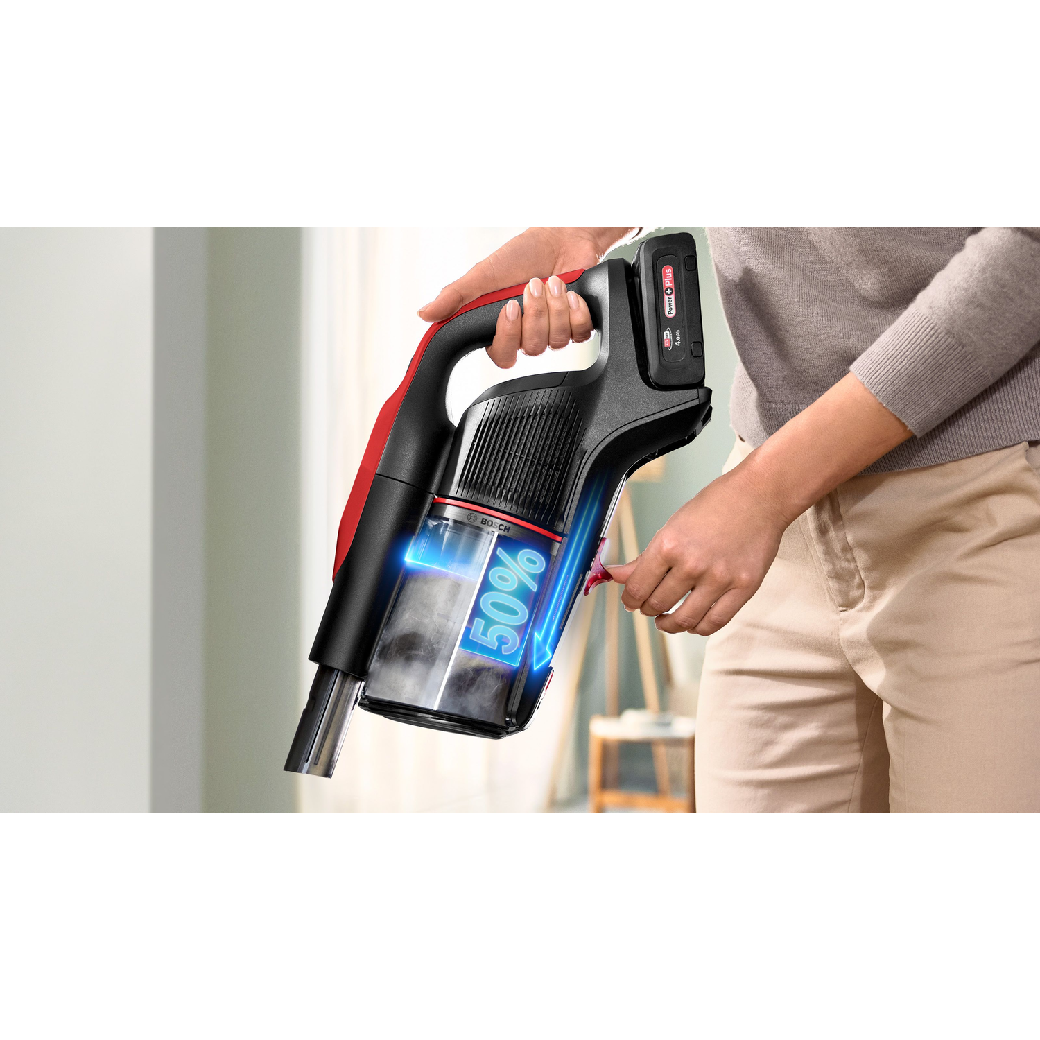 Person holding a black and red cordless vacuum cleaner, with a percentage display.