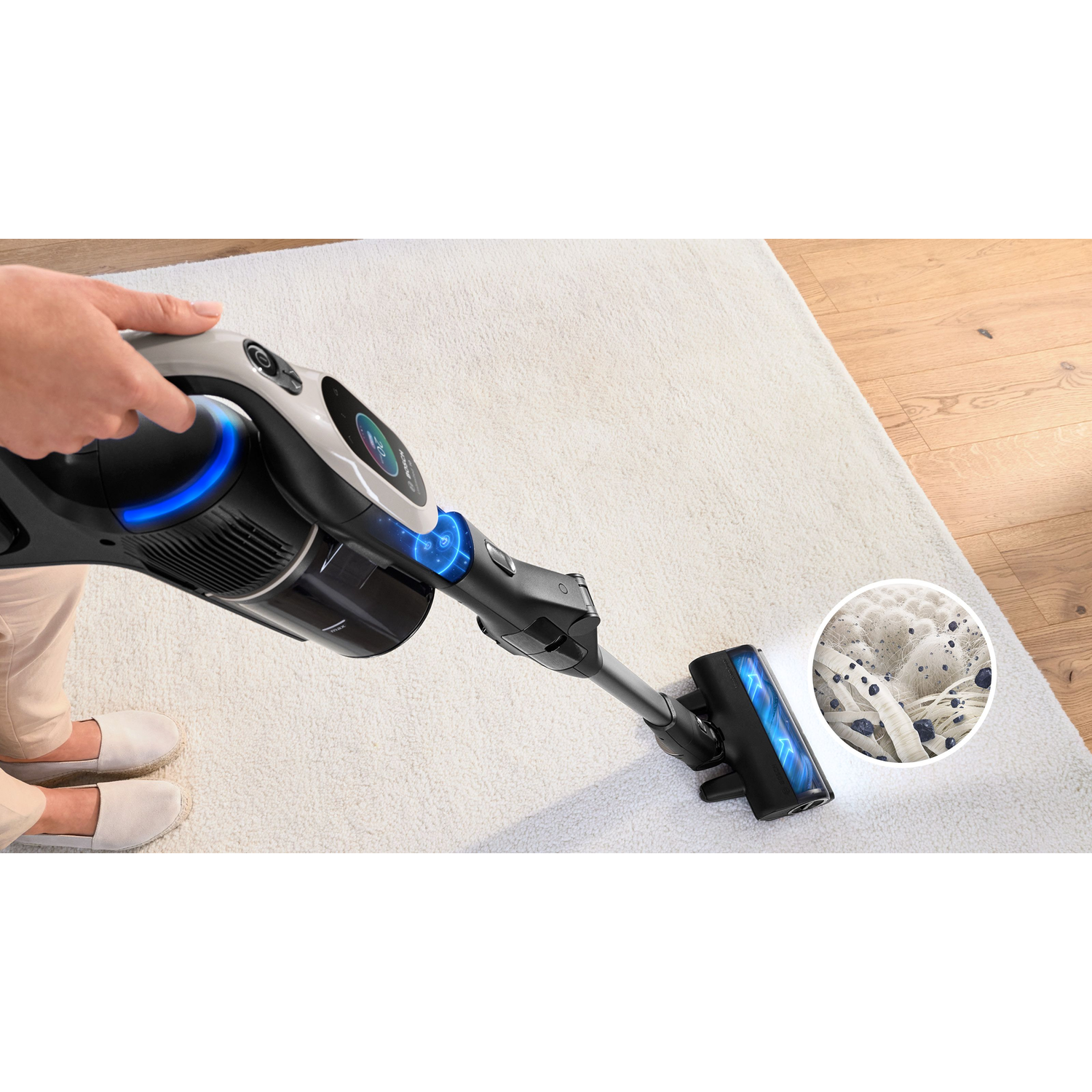 Person vacuuming a white carpet with a black and blue vacuum cleaner. Close-up of suction.