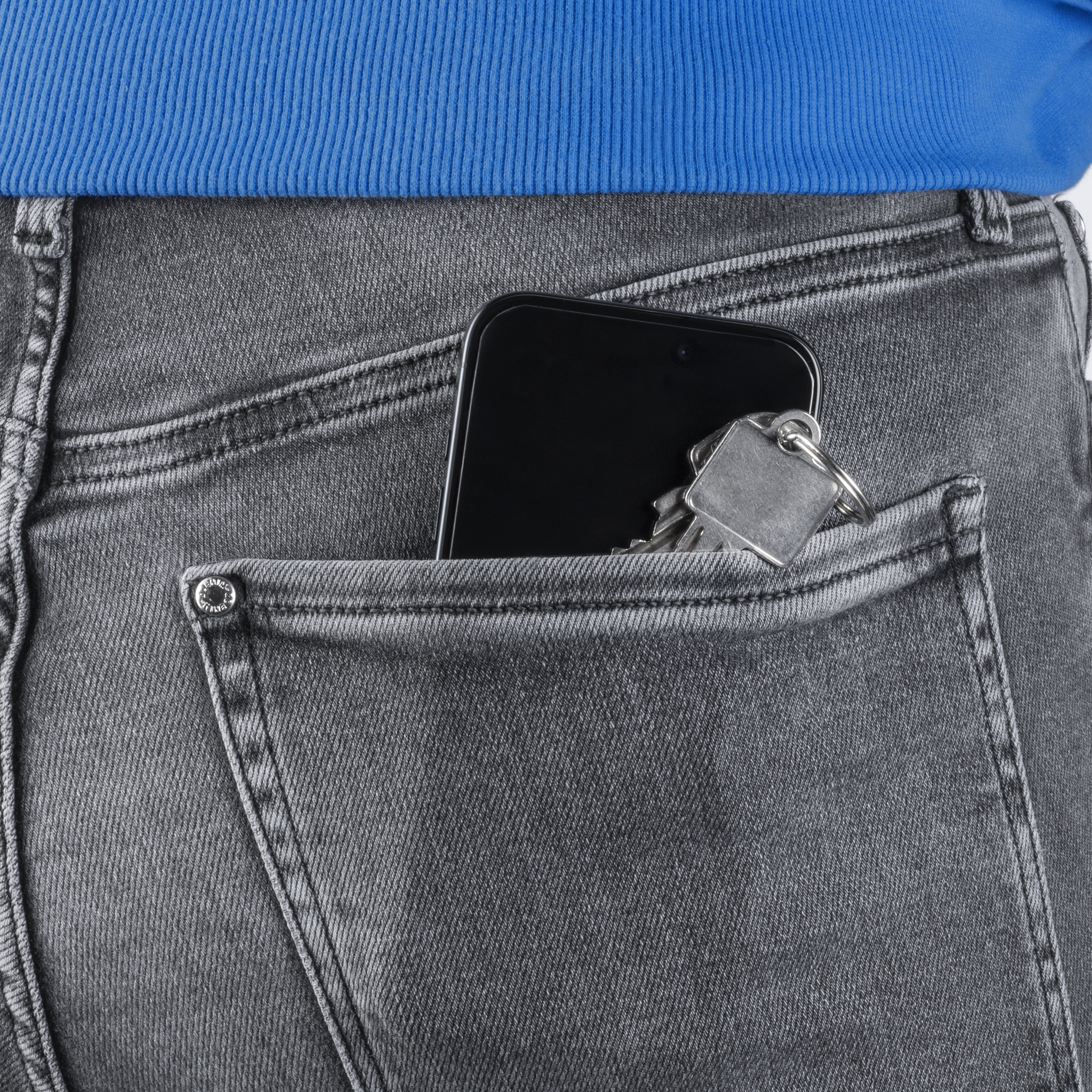 Smartphone und Schlüssel in der Hosentasche einer grauen Jeans, blauer Pullover.