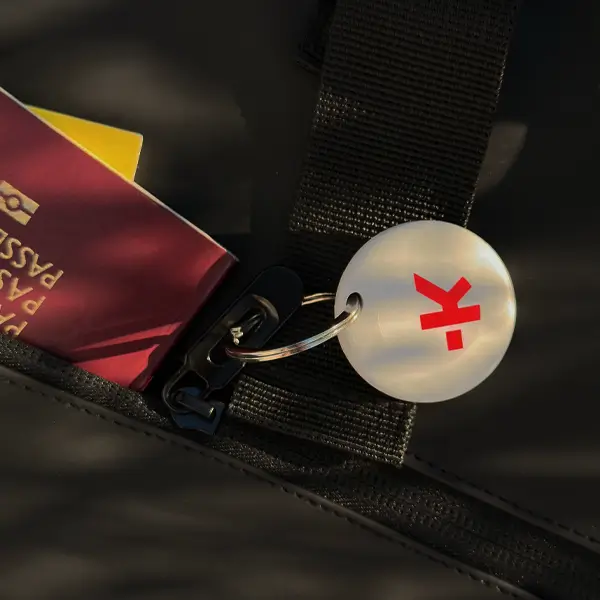 Una borsa nera con passaporto, portachiavi e un tag con una 'k' rossa.