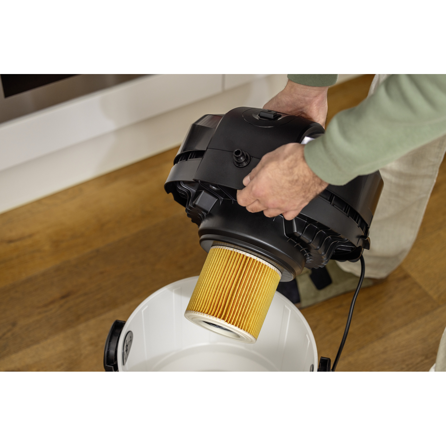 Une personne retirant un filtre d'un aspirateur noir.
